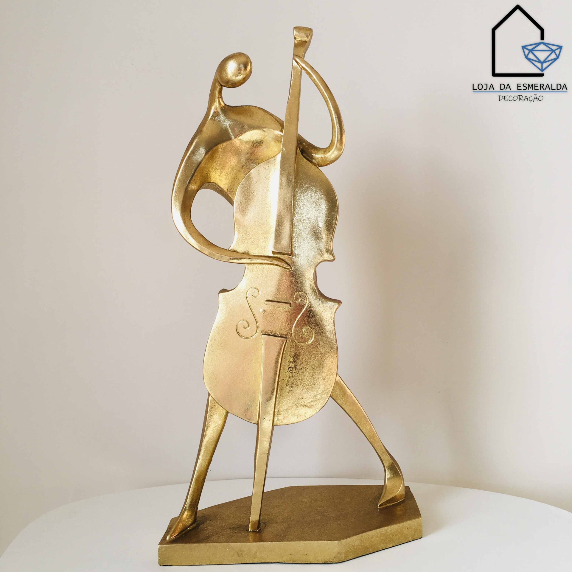 Escultura dourada abstrata em forma de violino com base retangular