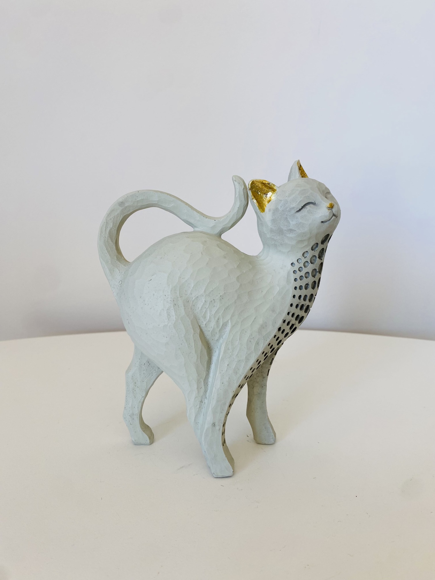 Estatueta de gato branco com detalhes dourados e pontos pretos