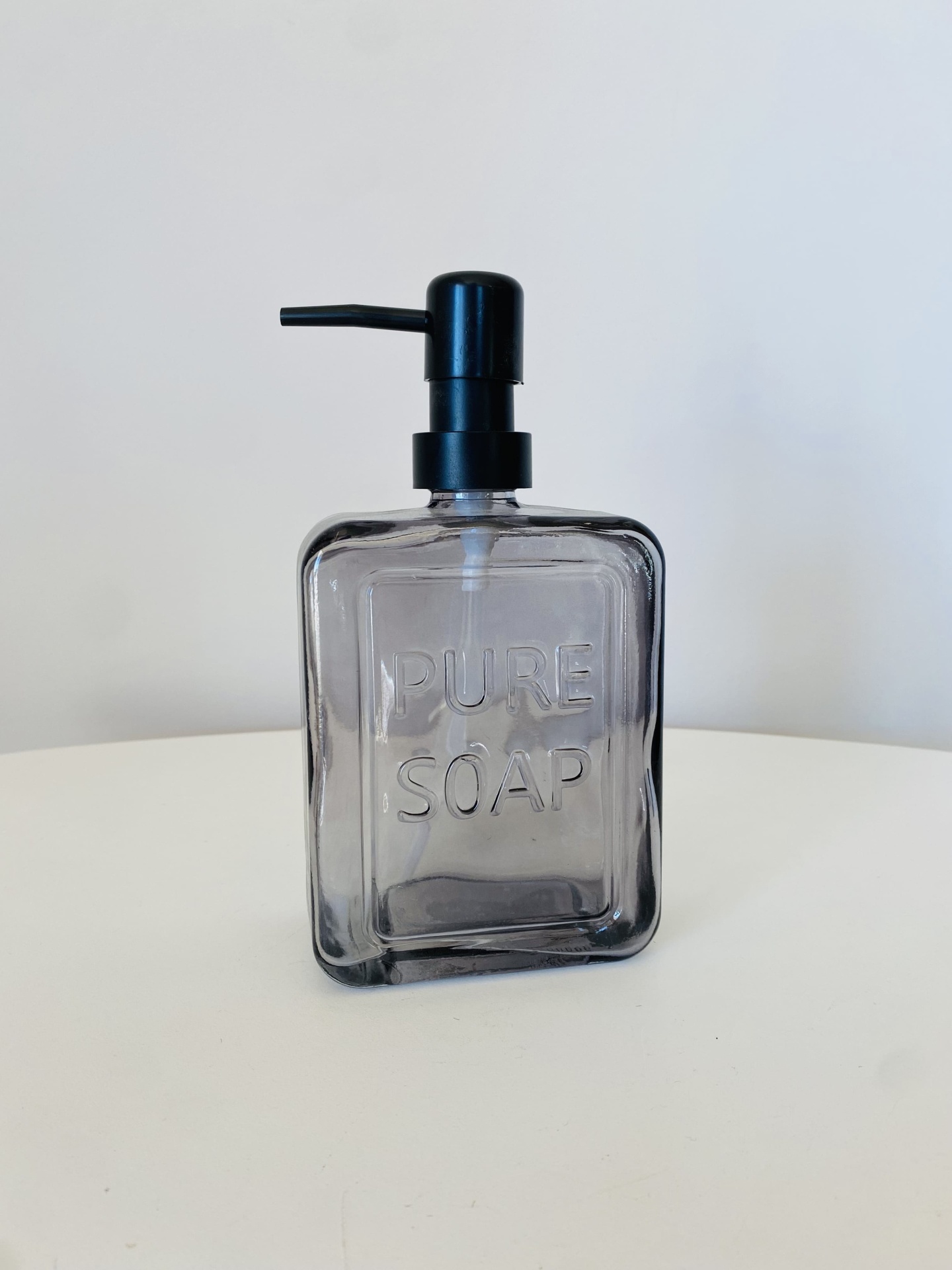 Frasco dispensador quadrado transparente com tampa preta e texto PURE SOAP em relevo.