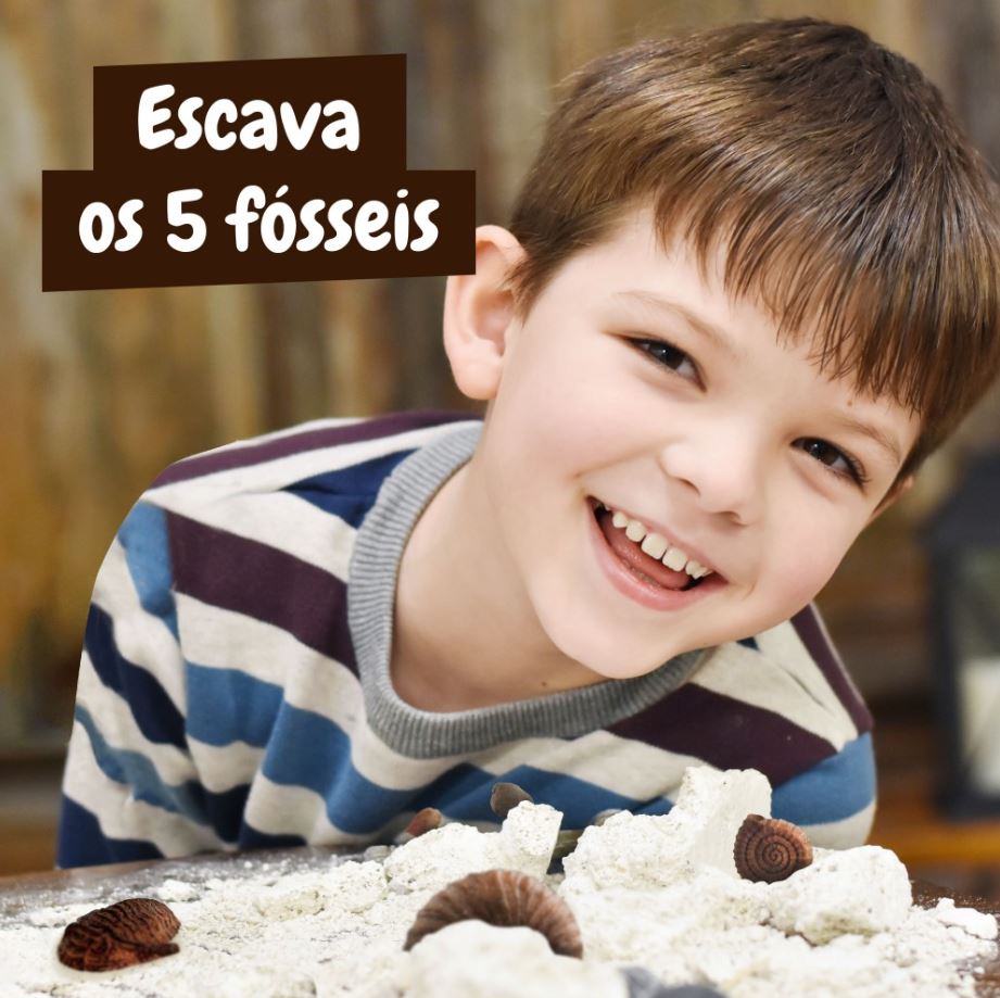 Criança sorridente com fósseis em material de areia para escavação