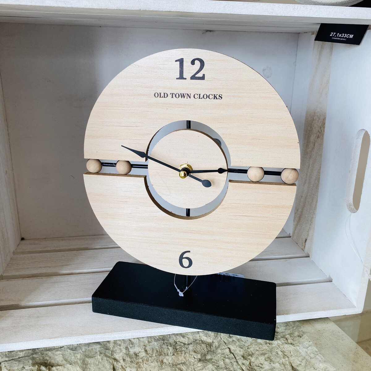 Relógio decorativo em madeira clara com base preta e números 12 e 6 visíveis