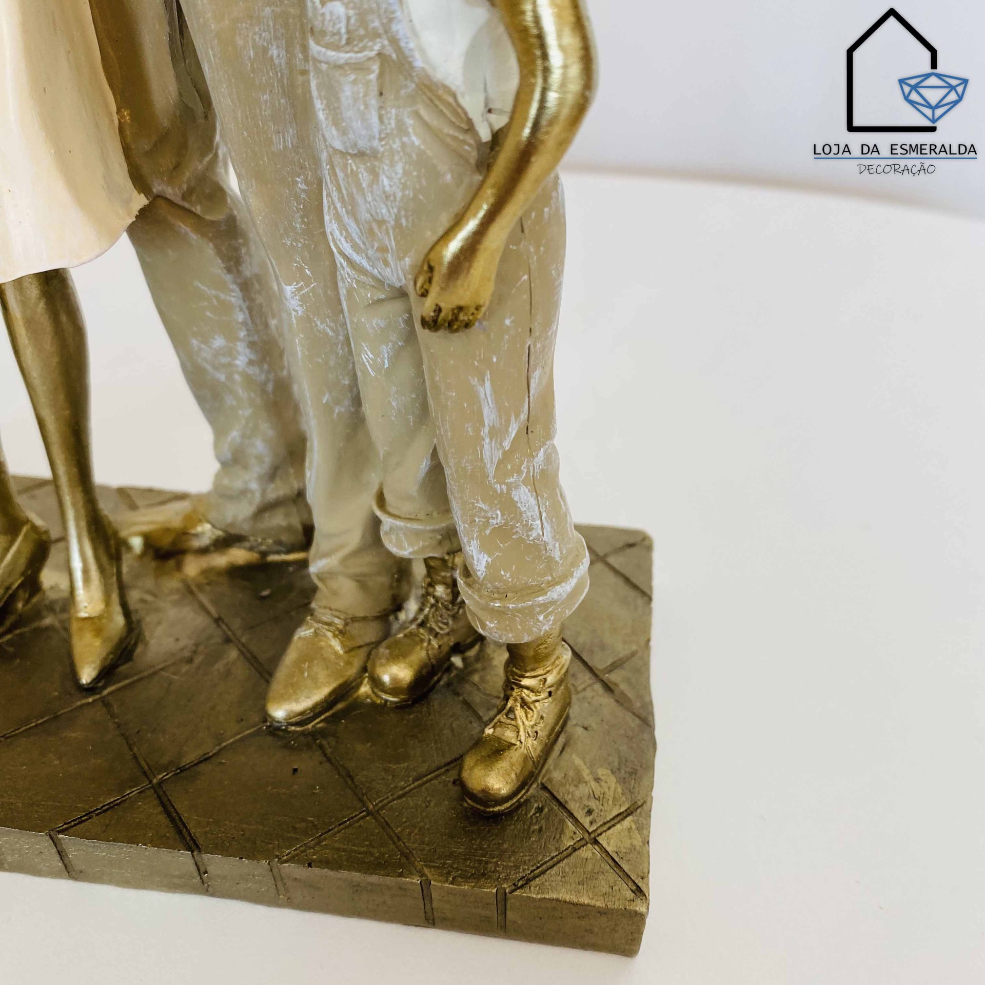 Figura decorativa com pés e pernas dourados sobre base quadrada com padrão de ladrilhos