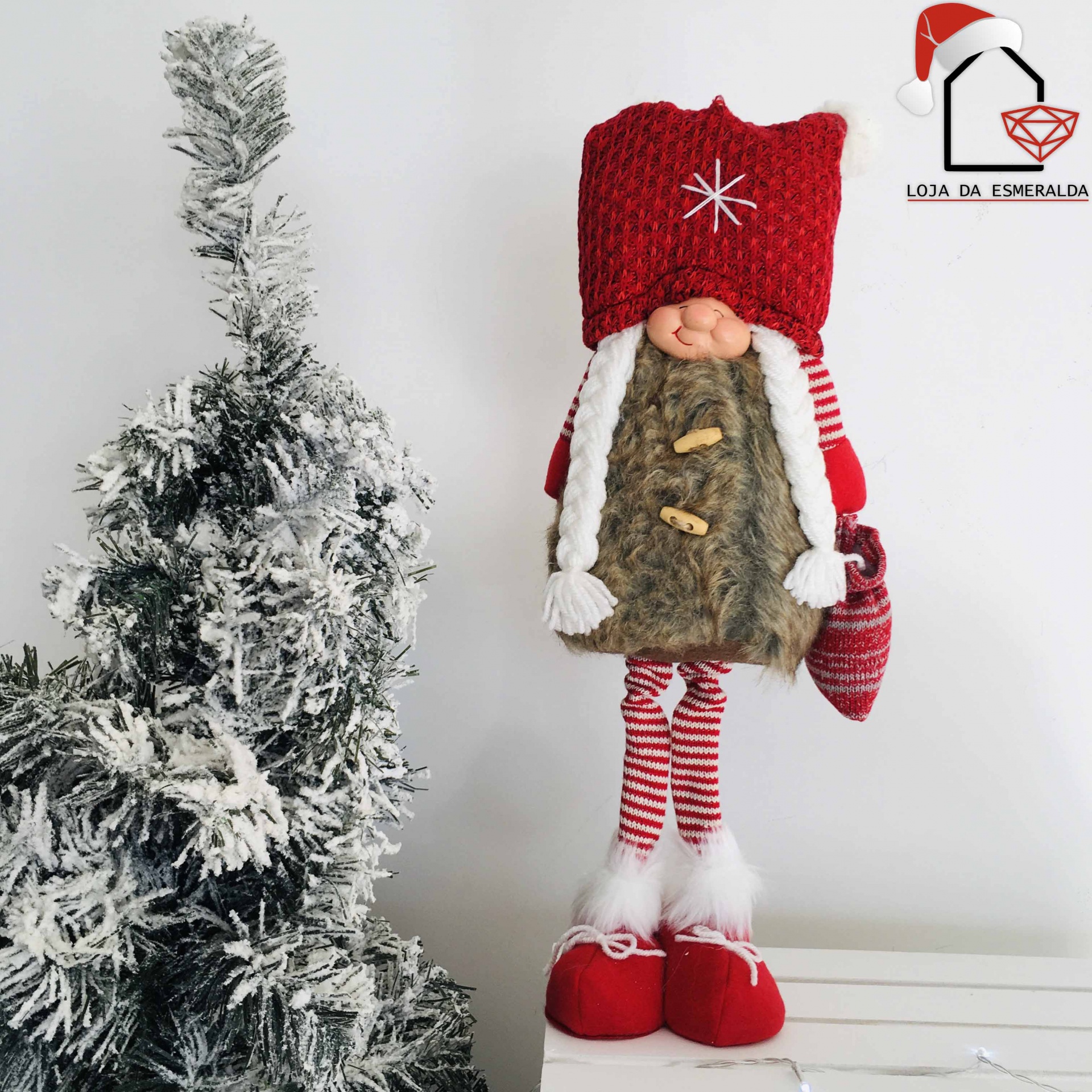 Boneco de Natal decorativo ao lado de árvore de Natal com neve falsa