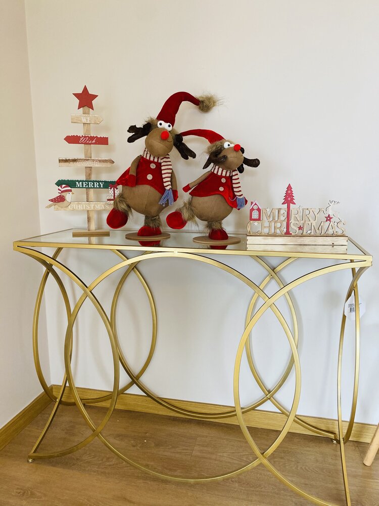 Consola dourada com decoração natalícia incluindo renas de peluche e texto Merry Christmas