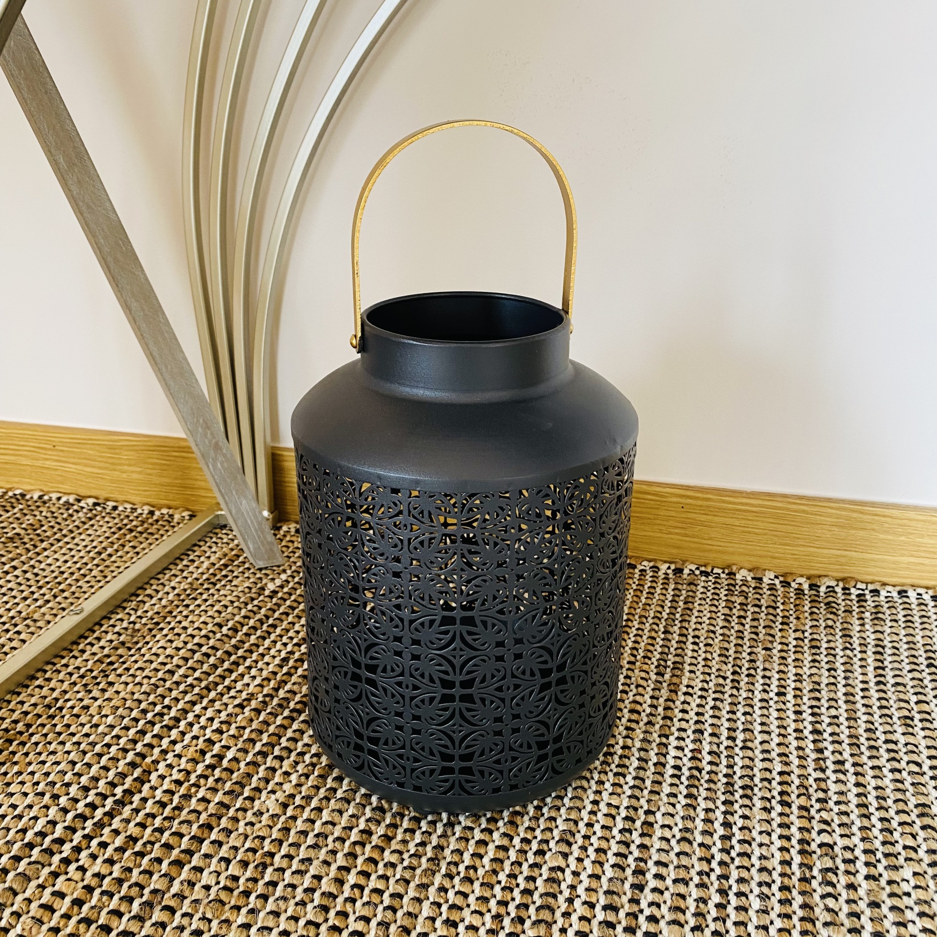 Lanterna preta em metal com alça de corda sobre tapete rústico