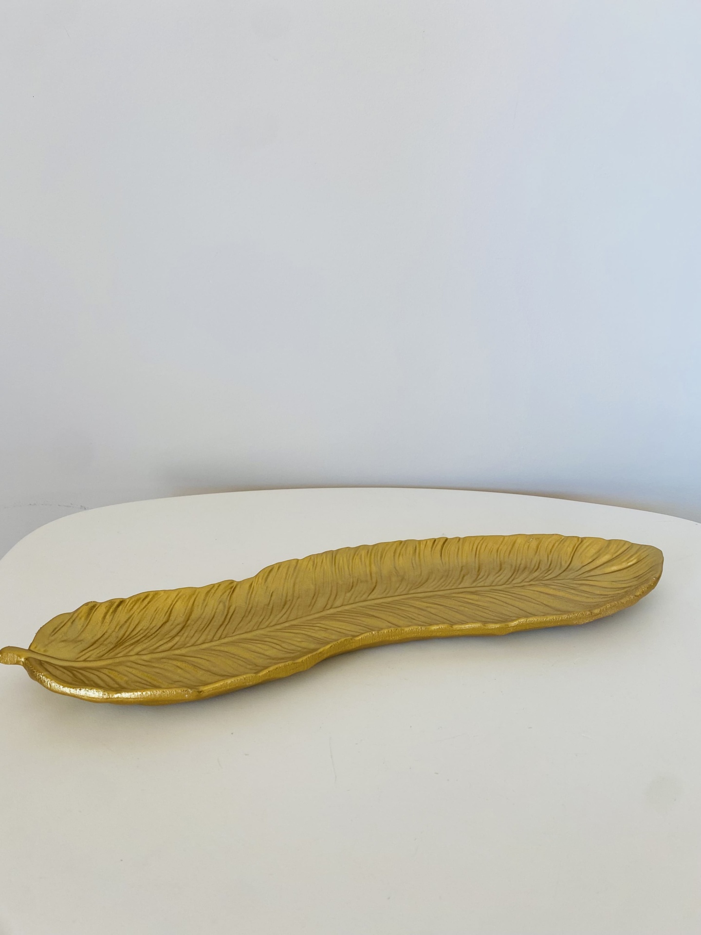 Prato decorativo dourado em forma de folha.