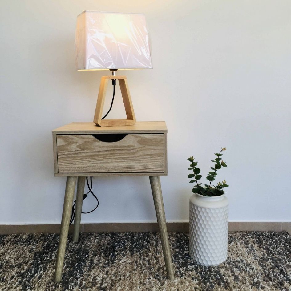 Mesa de cabeceira com lâmpada e vaso decorativo.