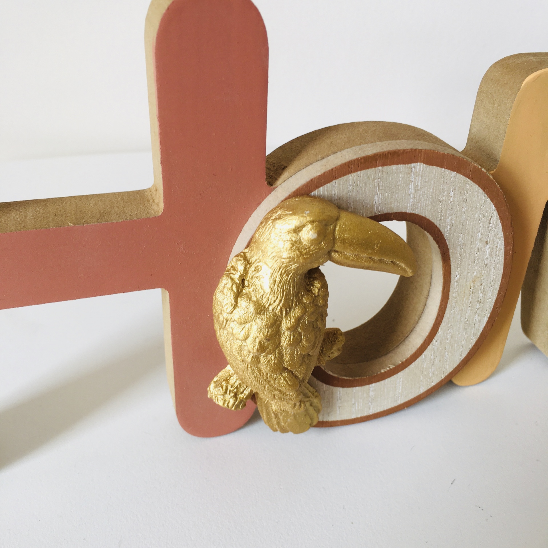 Letra decorativa em madeira com pássaro dourado em relevo