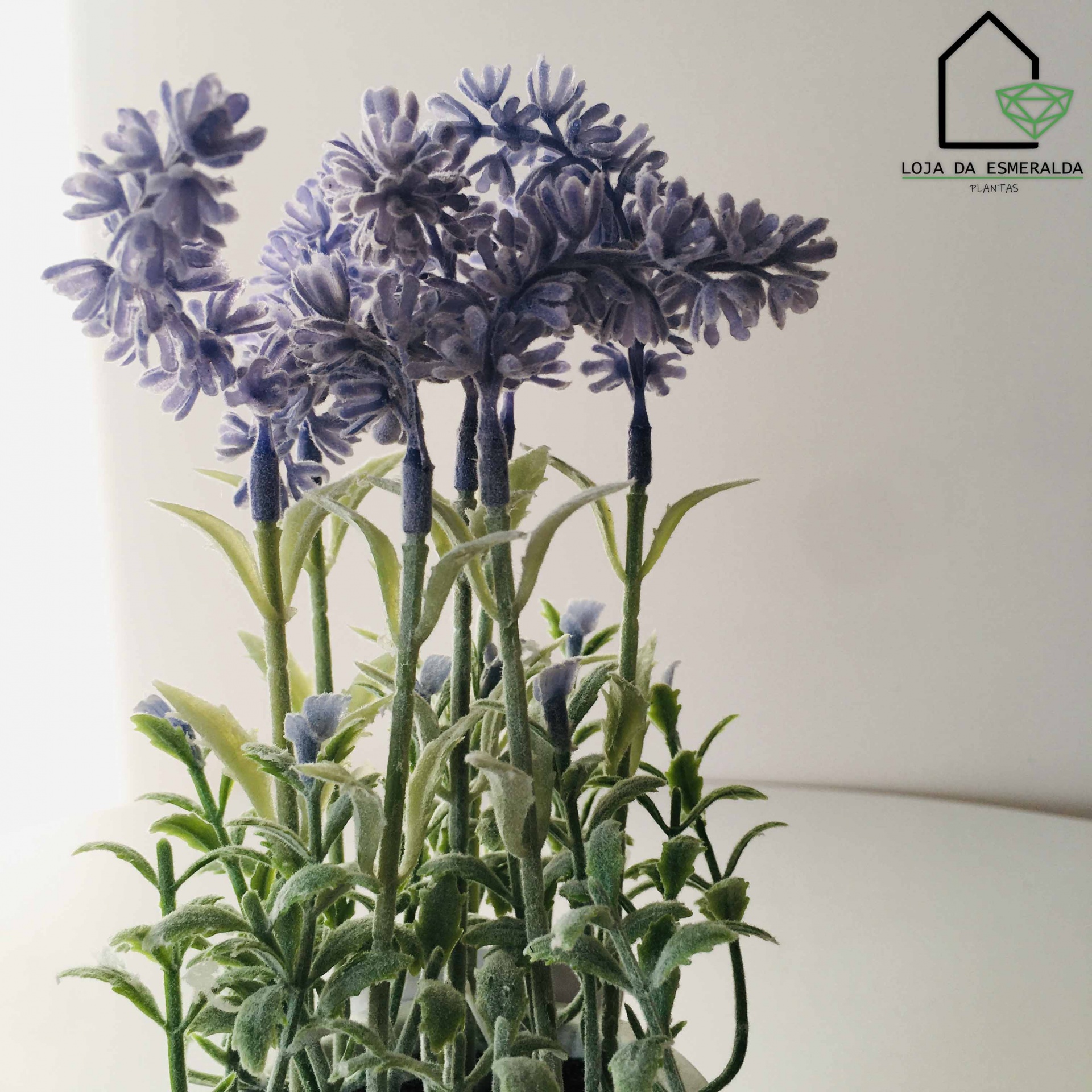 Arranjo de plantas artificiais com flores lilases e folhas verdes