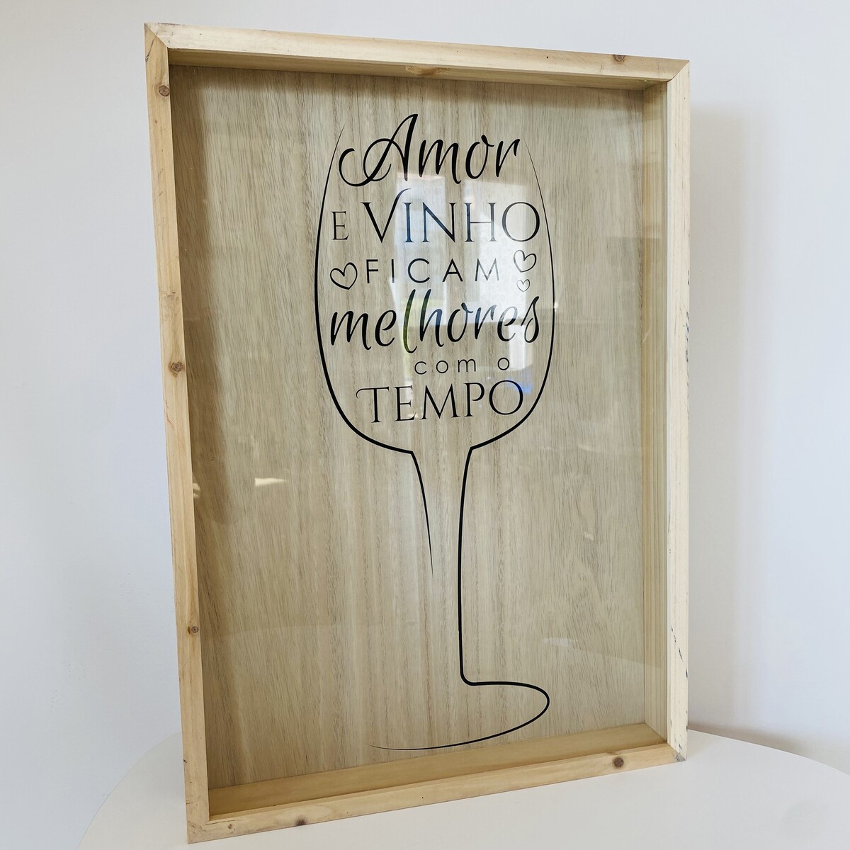 Quadro de madeira com vidro e mensagem sobre amor e vinho.