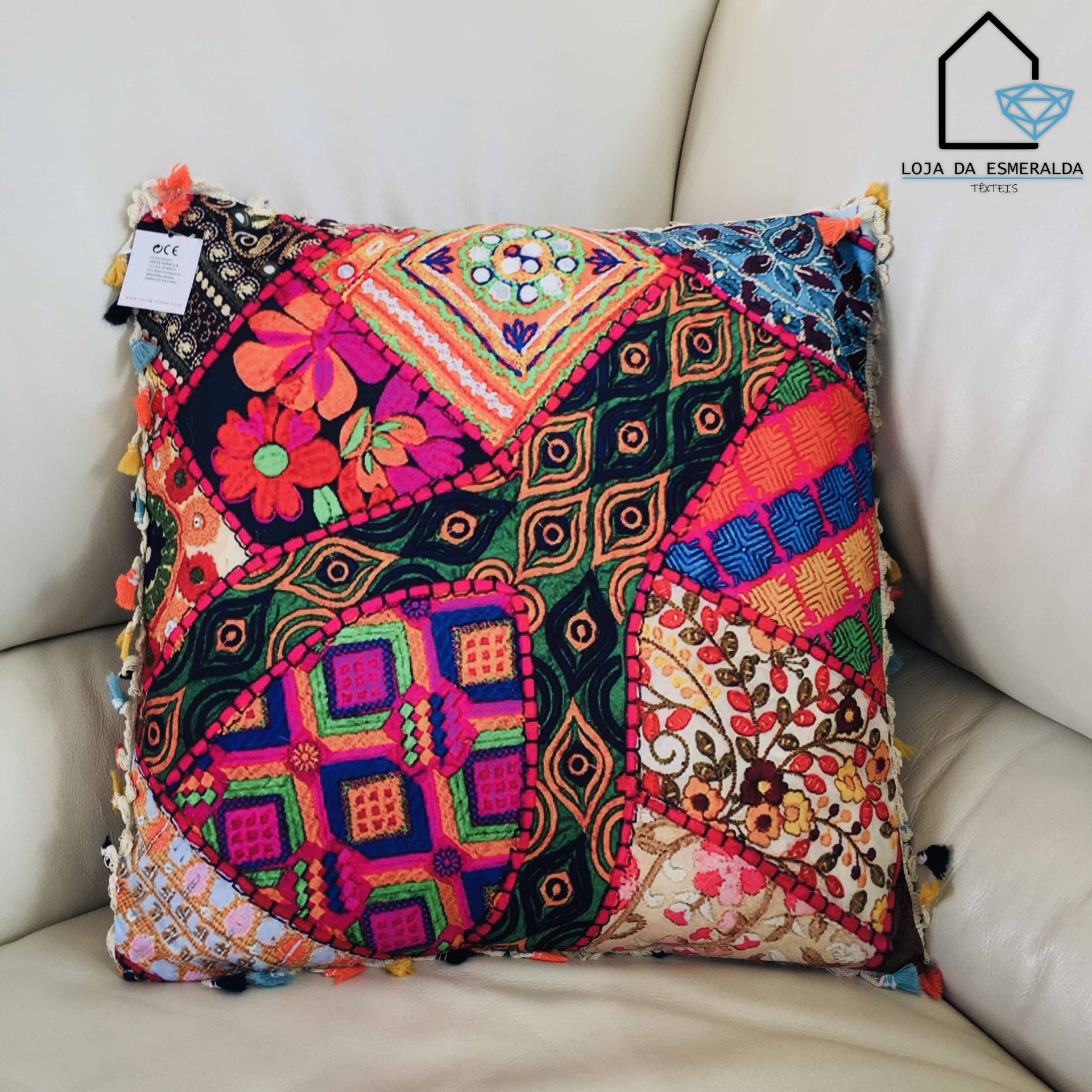 Almofada decorativa com padrões coloridos e franjas num sofá bege