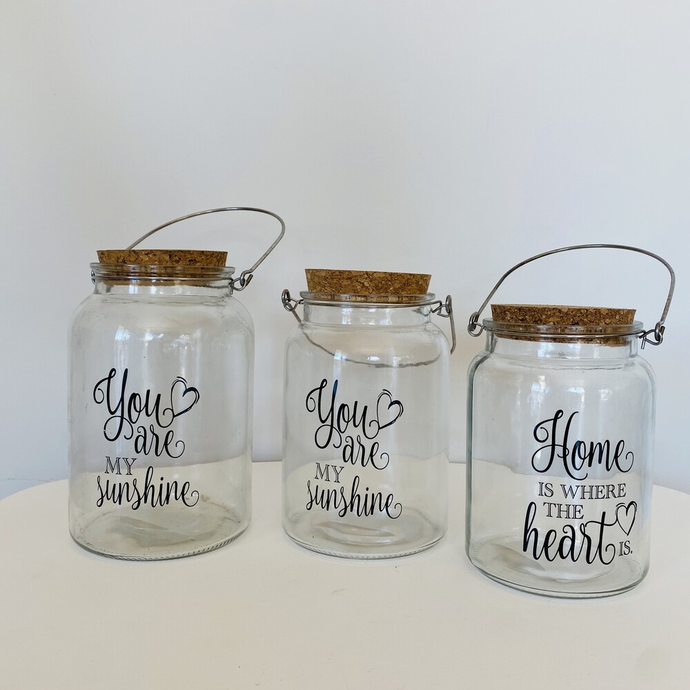 Três frascos de vidro com tampas de cortiça e inscrições em preto