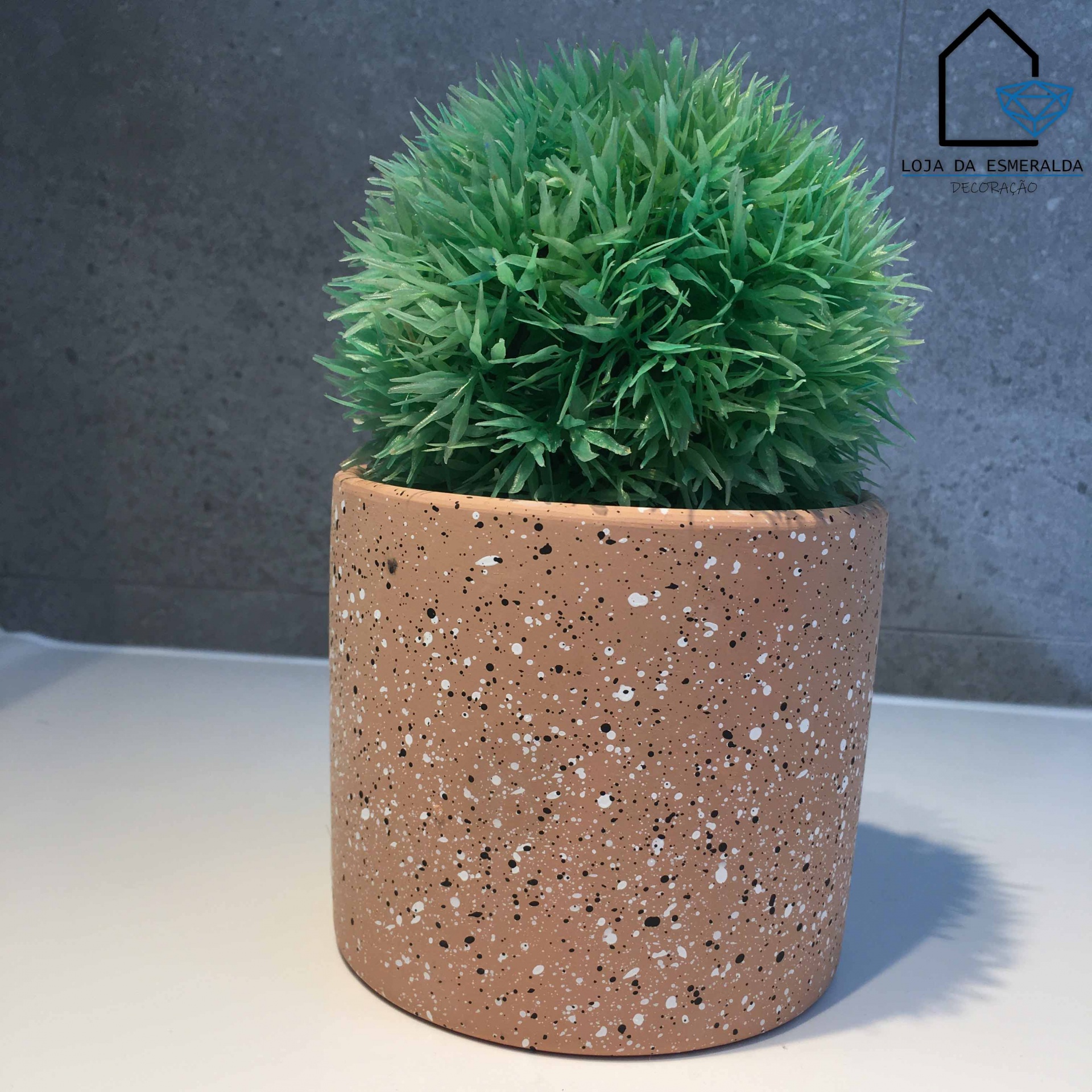 Vaso de terracota com planta artificial verde num fundo cinza