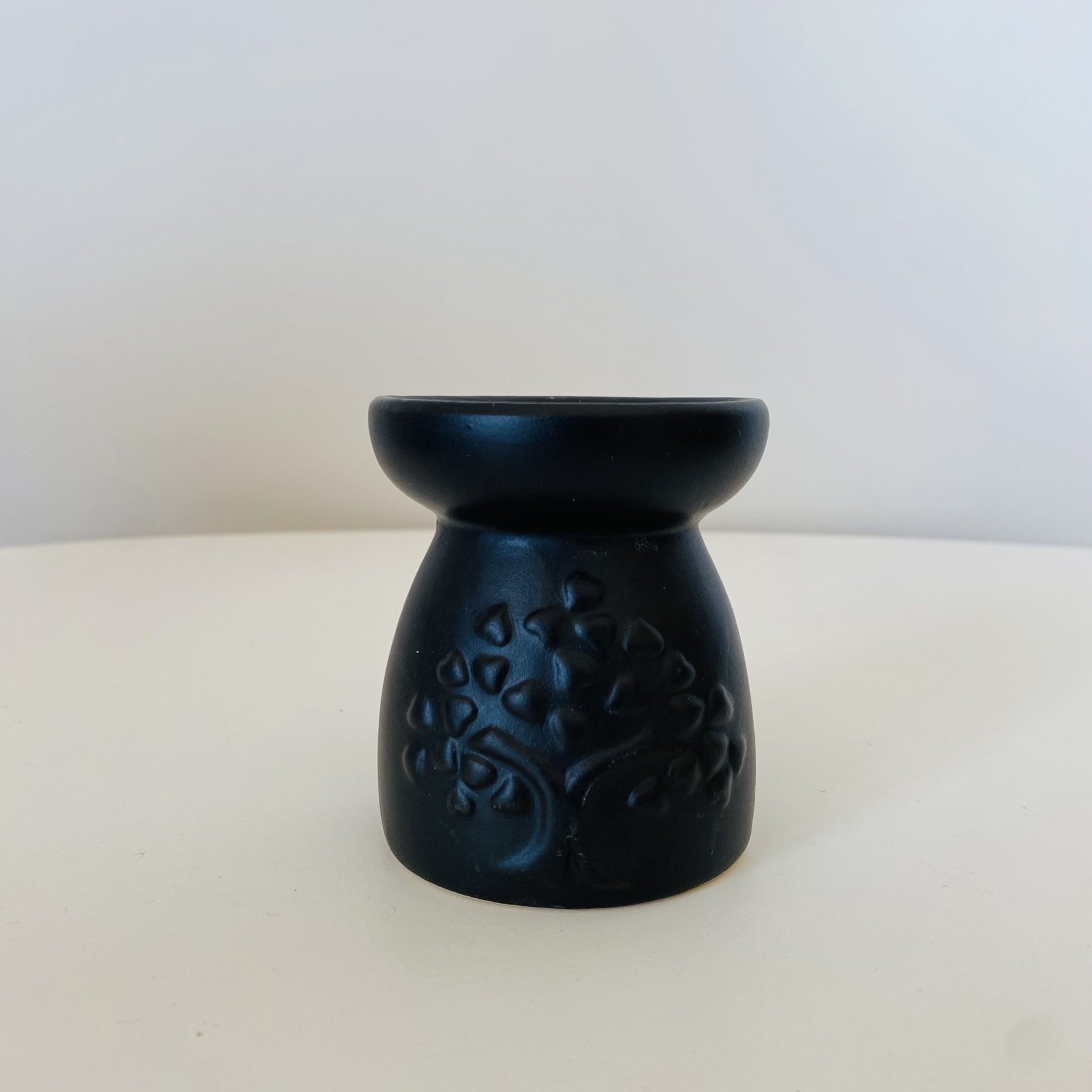 Suporte preto com relevo de árvore em superfície branca