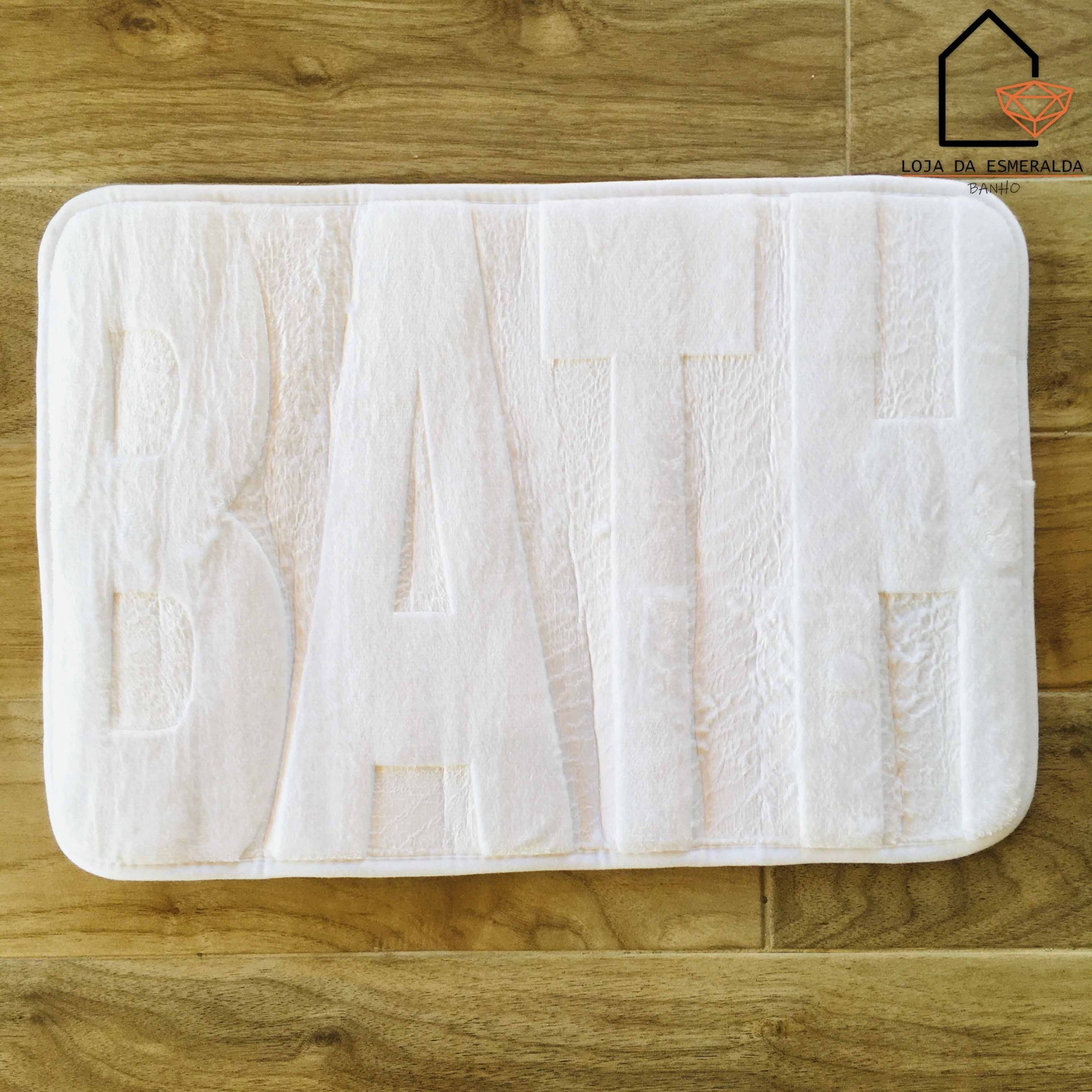 Tapete de banho branco com a palavra BATH em relevo sobre chão de madeira