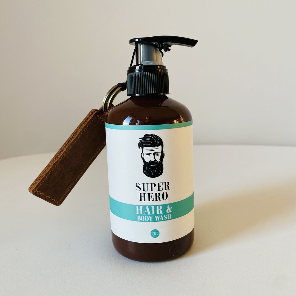 Frasco castanho com tampa bomba e rótulo branco e azul de produto para cabelo e corpo