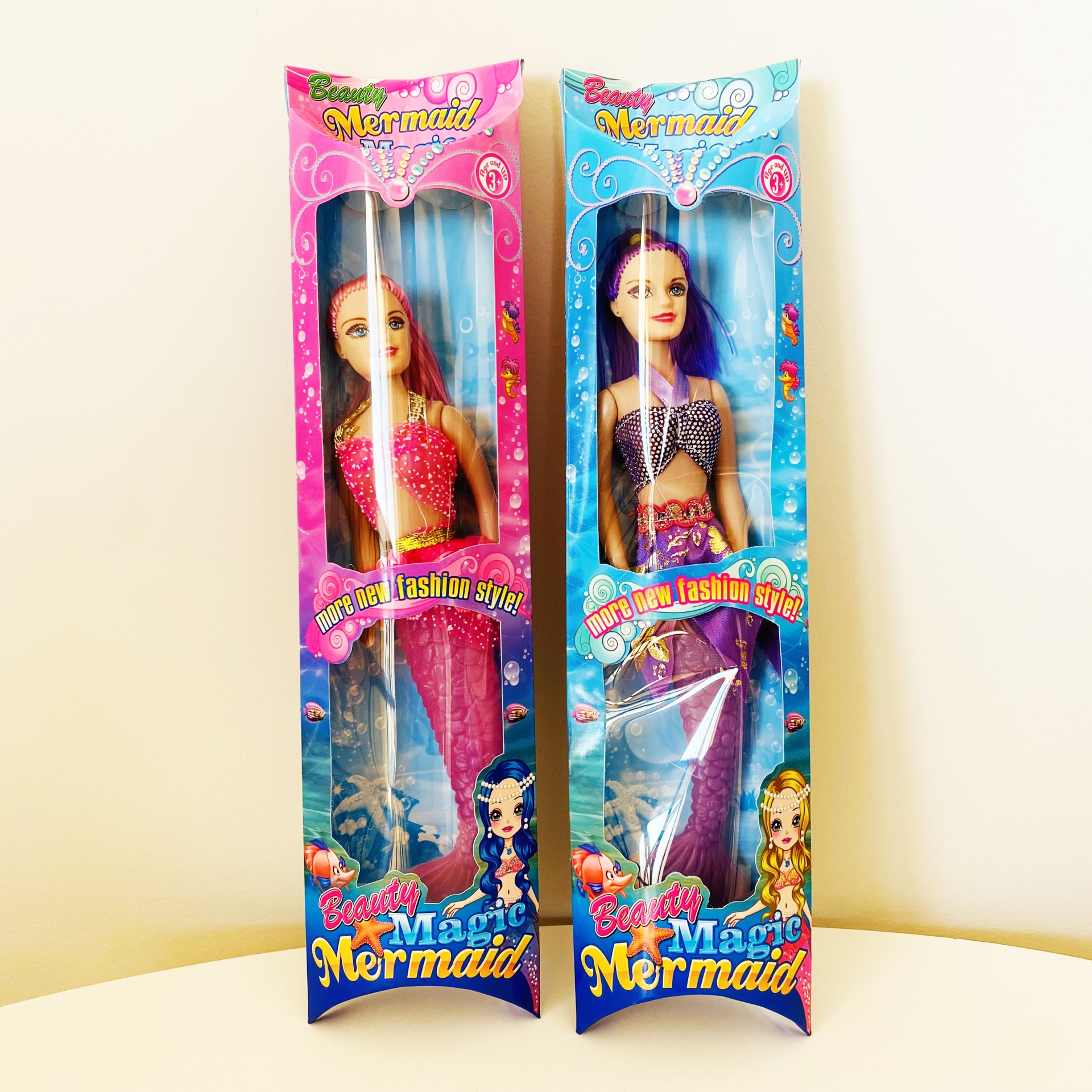 Duas bonecas de sereia em embalagens coloridas com textos Beauty Magic Mermaid