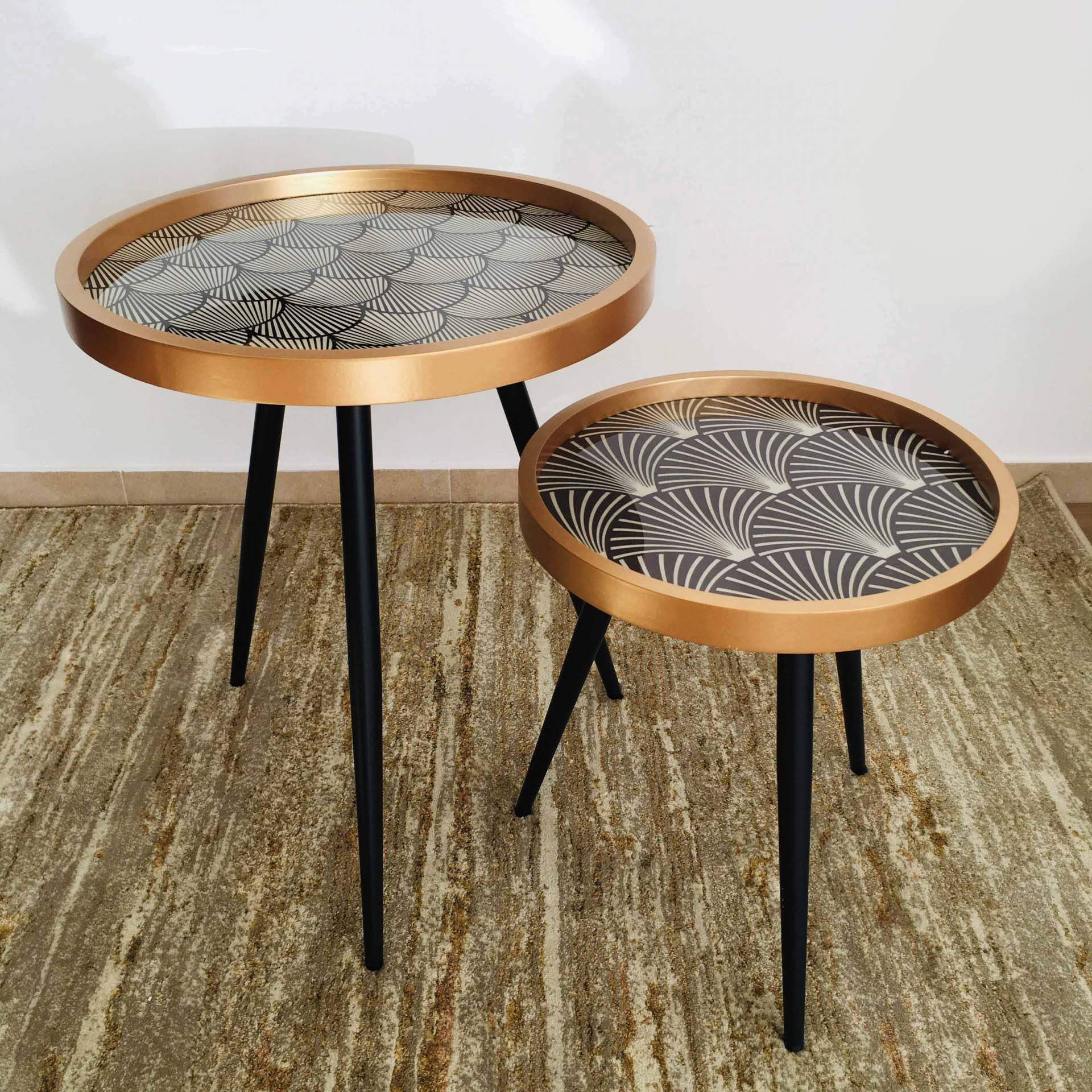 Duas mesas auxiliares redondas com tampo geométrico e pernas pretas.
