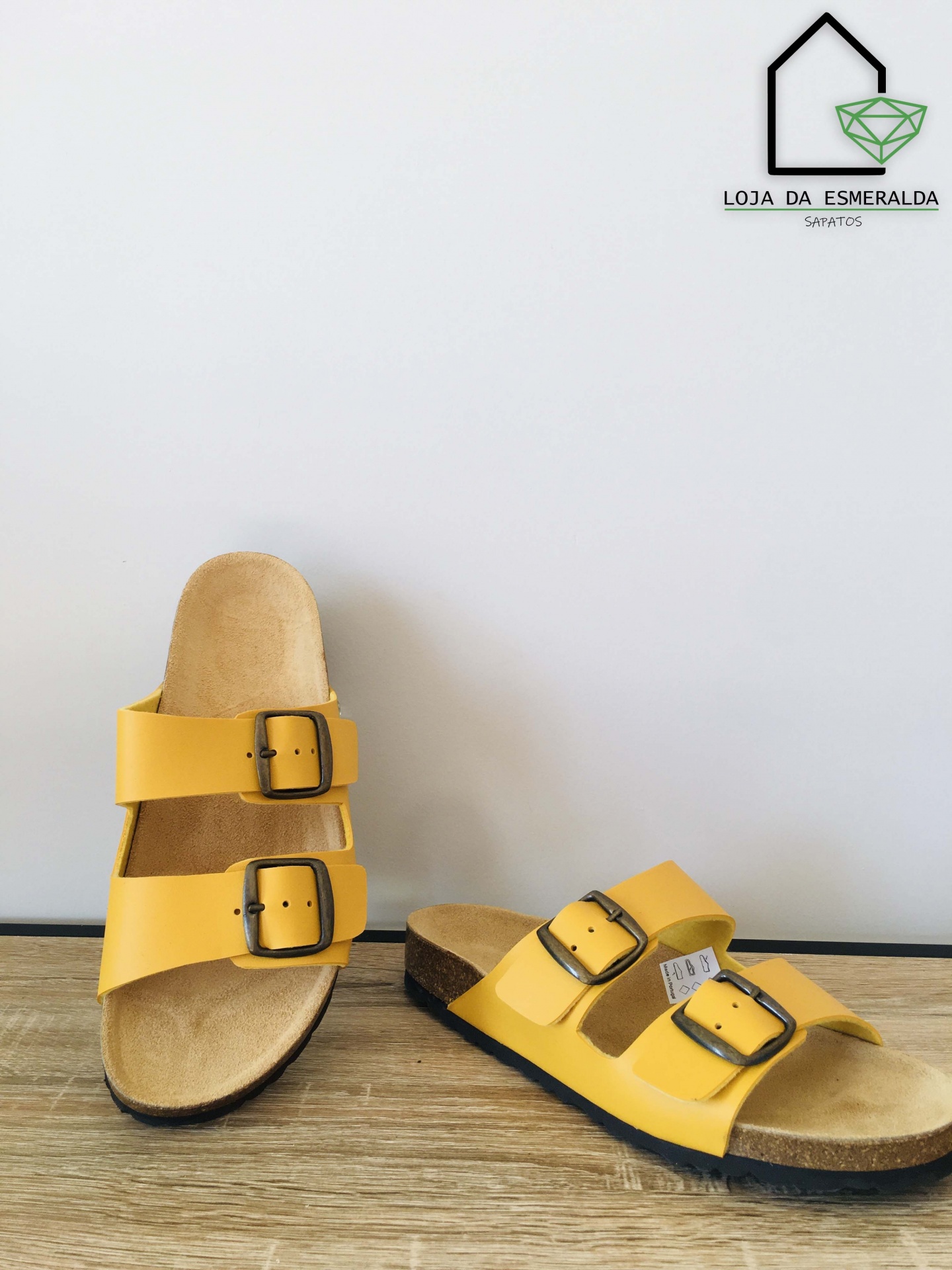 sandálias amarelas com fivelas sobre superfície de madeira