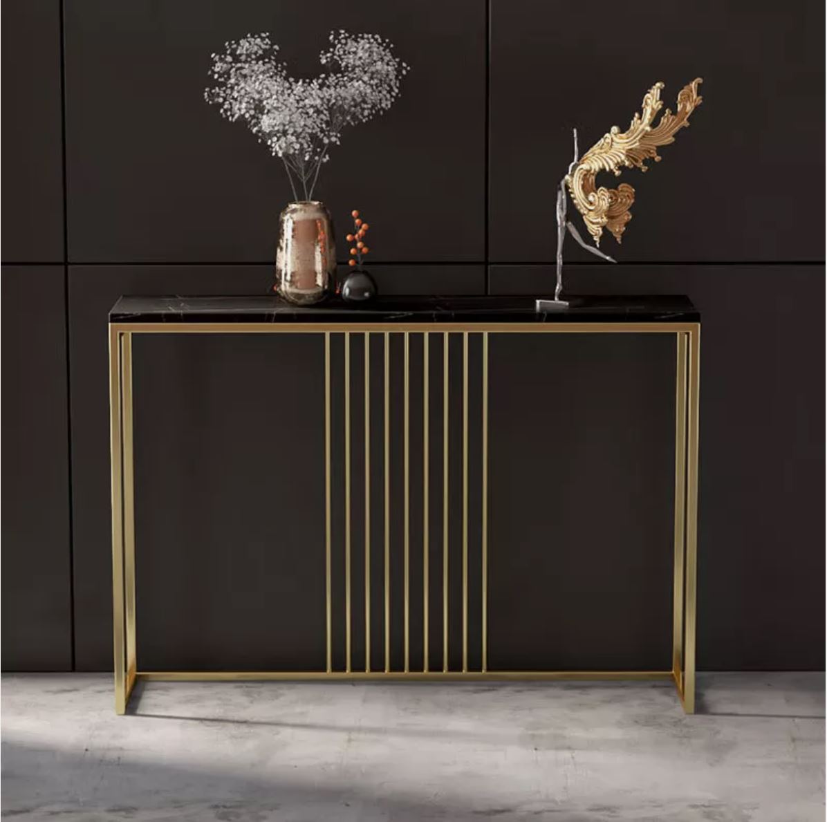 Aparador dourado com tampo preto e decorações em vaso e objeto dourado