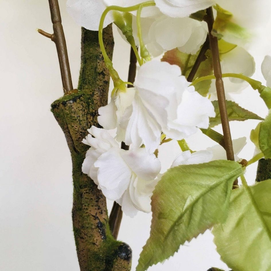 Flores artificiais brancas com folhas verdes e ramos castanhos texturizados