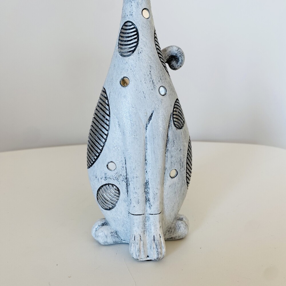 Estatueta cerâmica branca com manchas pretas e brancas sobre superfície branca