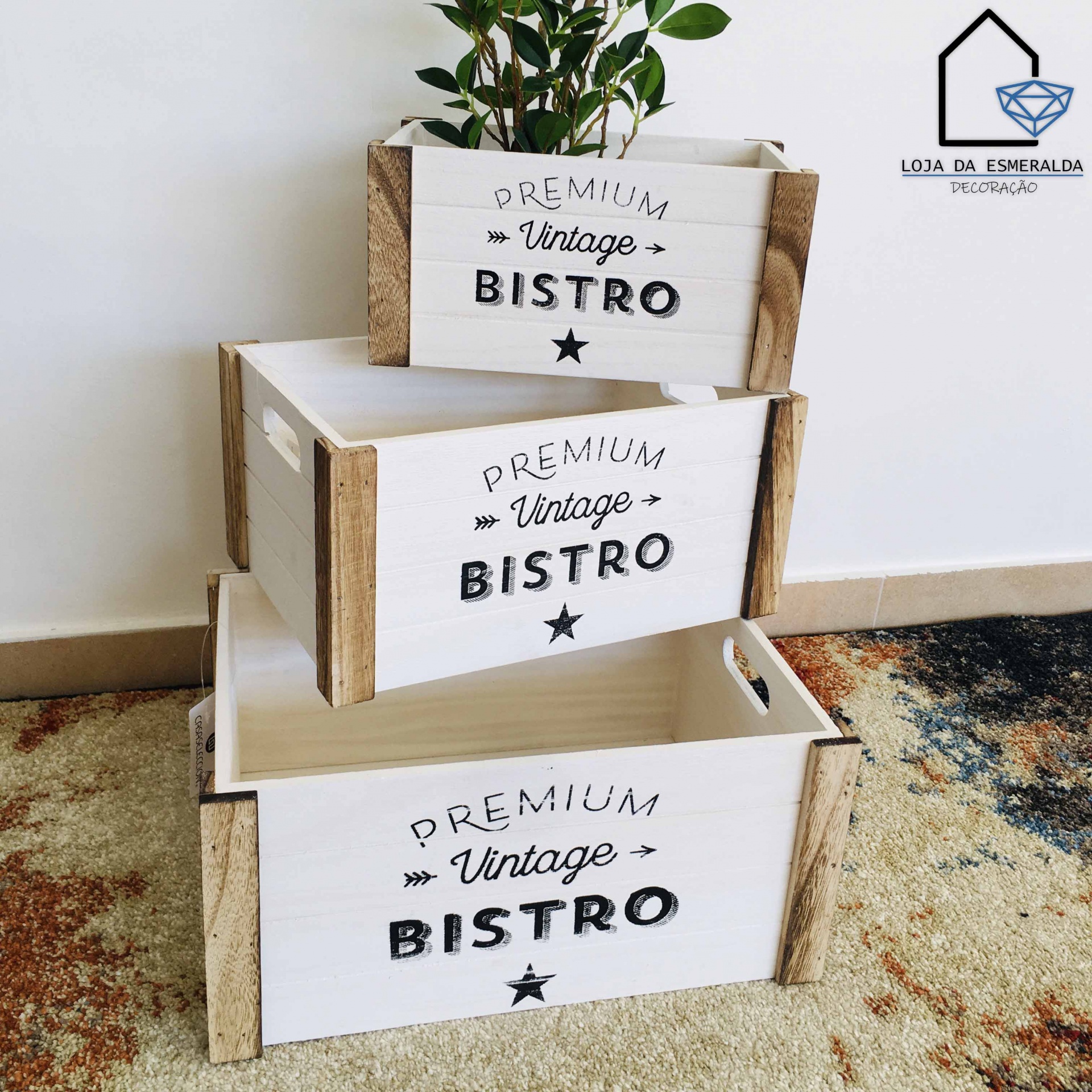 Três caixas de madeira branca e natural com texto 'PREMIUM Vintage BISTRO', empilhadas e com planta ao fundo.