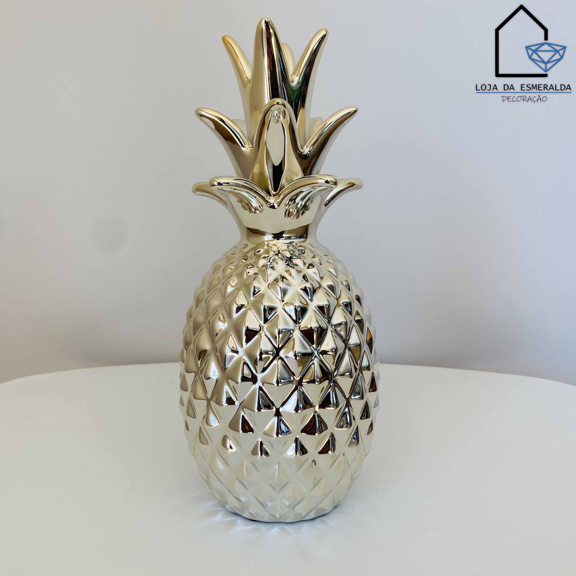 Vaso decorativo em forma de ananás dourado numa mesa branca
