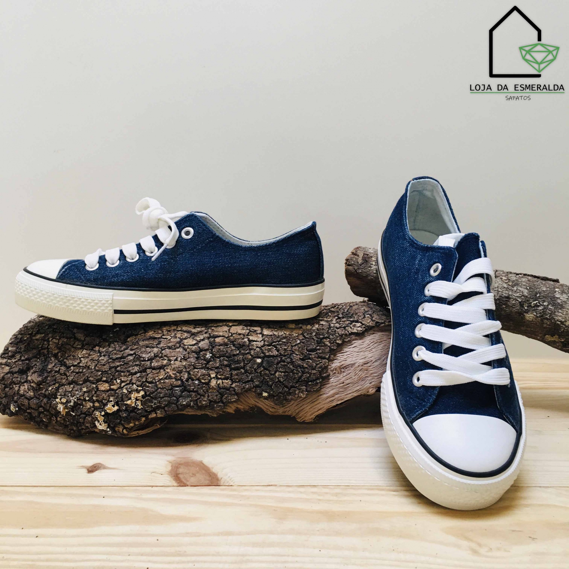 Par de ténis azuis com sola e bico brancos sobre tronco de madeira