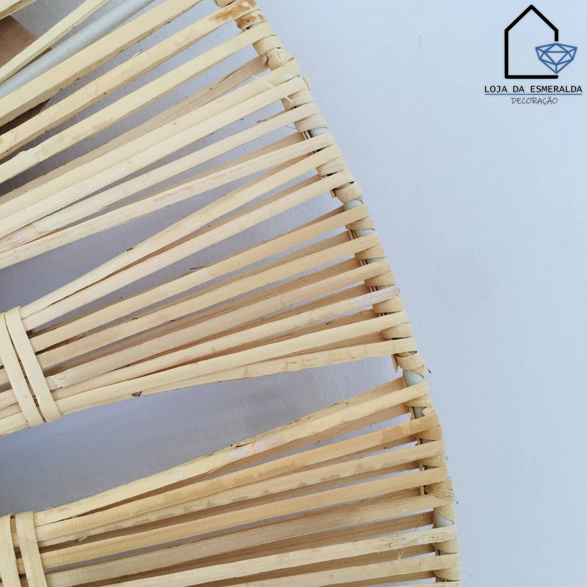 Peça decorativa de madeira clara circular com varetas espaçadas, com logótipo de loja no canto superior direito