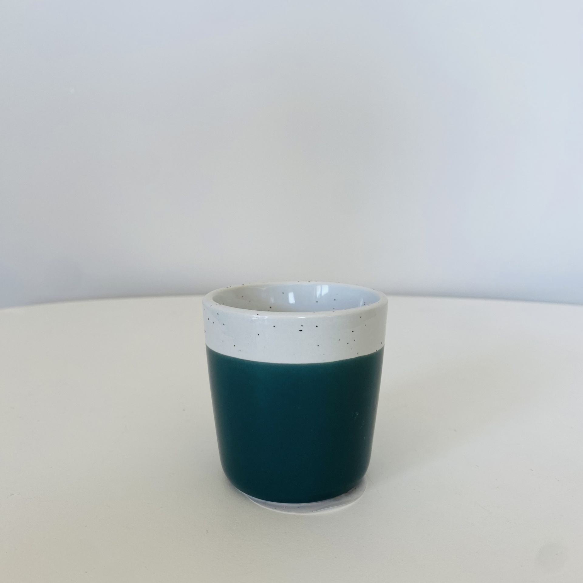 Copo de cerâmica verde escuro com bordo branco e pontos pretos