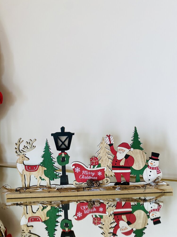 Figuras decorativas de Natal em madeira sobre superfície refletora