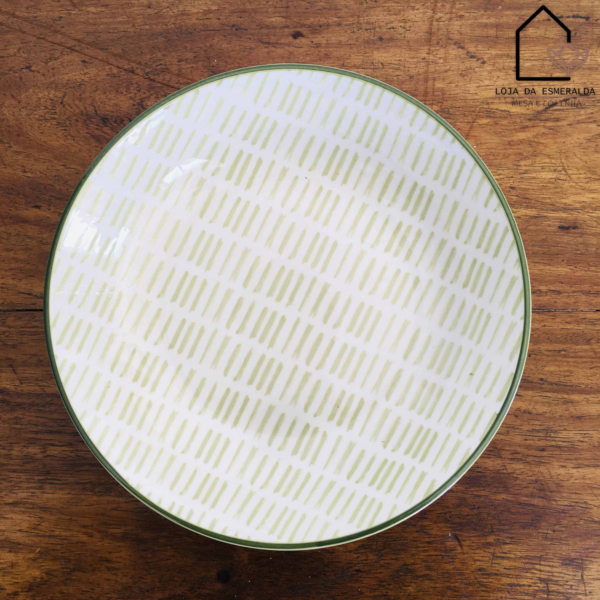 Prato de cerâmica branco com padrão verde sobre mesa de madeira
