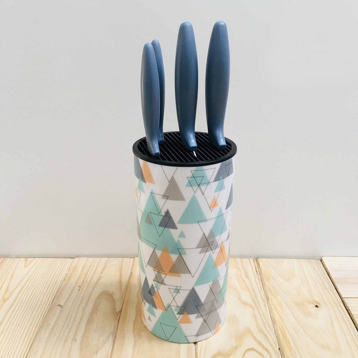 Conjunto de facas com cabos azuis em suporte com padrão geométrico multicolor sobre mesa de madeira