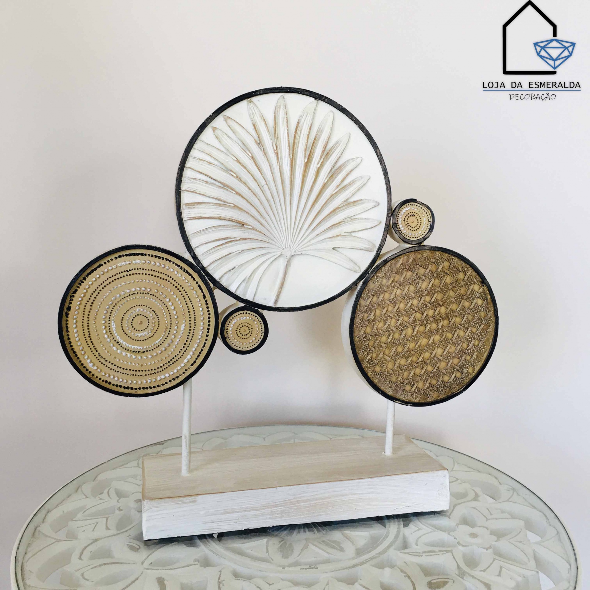 Escultura decorativa com discos circulares e base branca sobre mesa de vidro