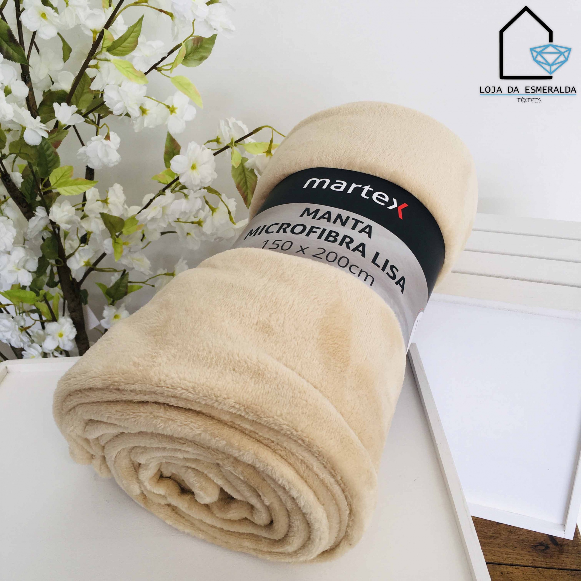 Manta de microfibra lisa bege enrolada com etiqueta da marca Martex