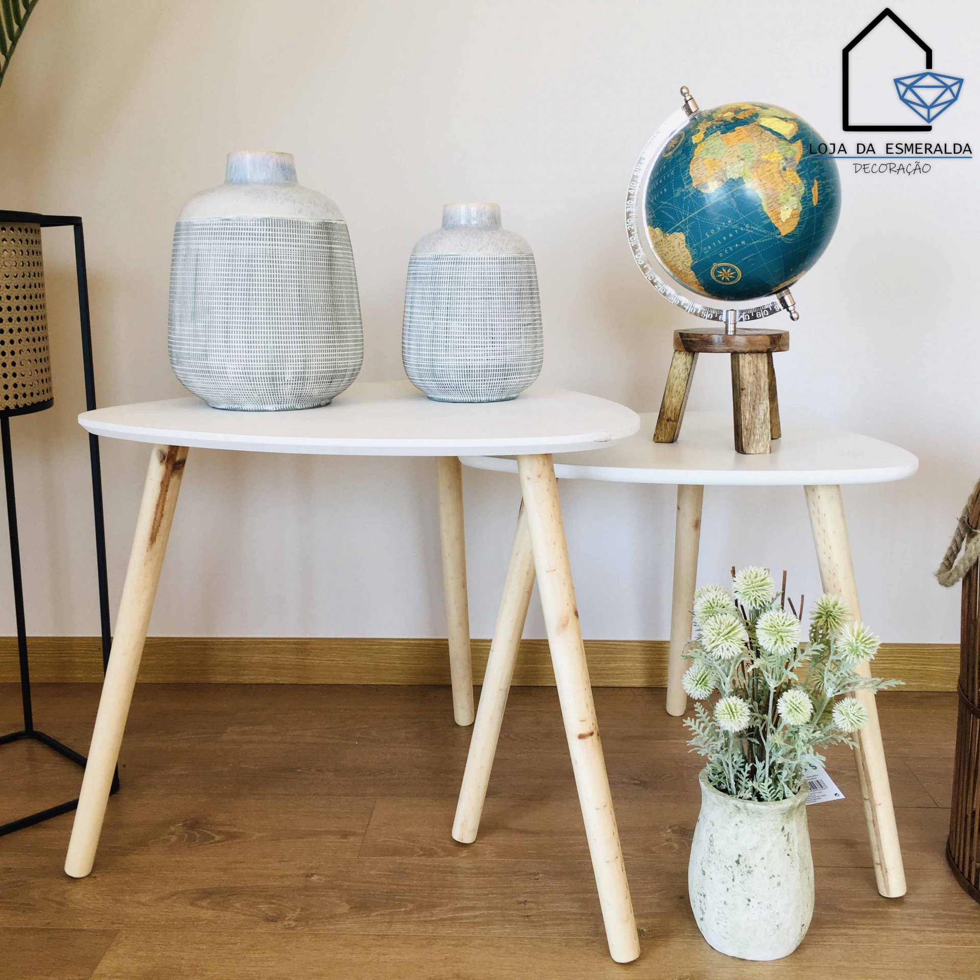 Duas mesas brancas com decoração de potes, globo e vaso com flores