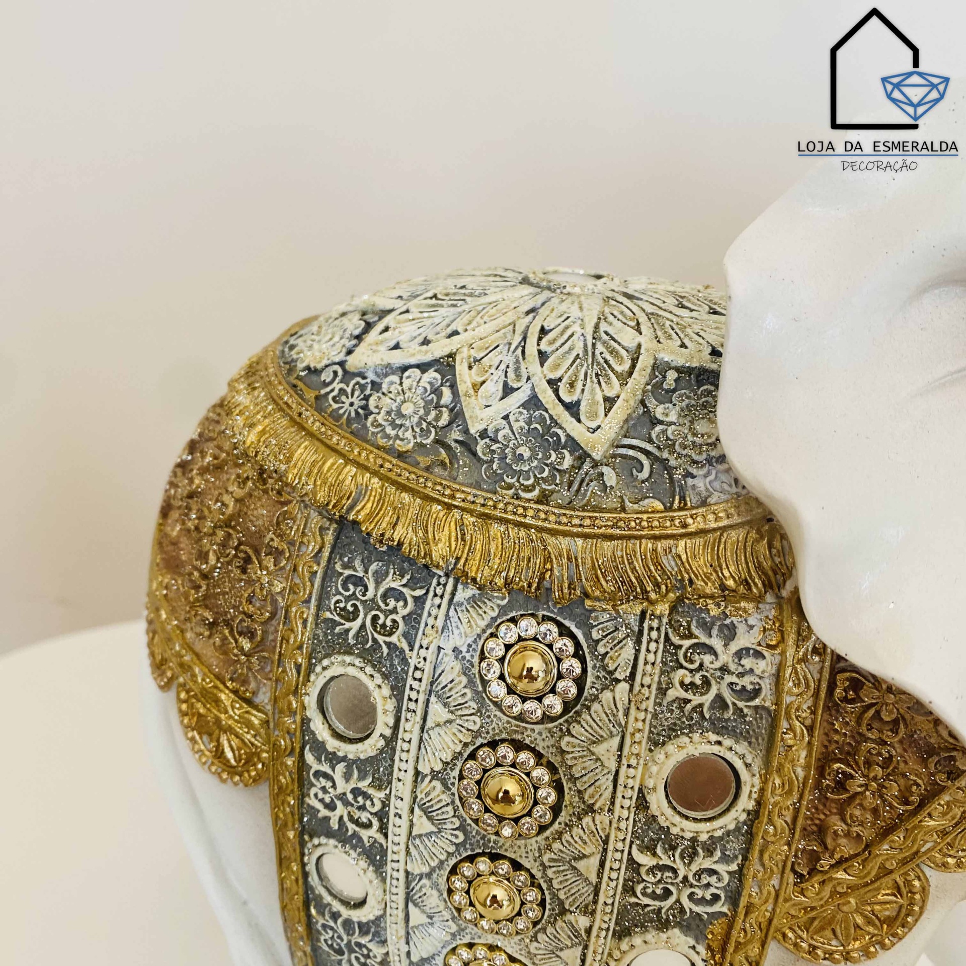Cabeça decorativa de elefante com padrão dourado e cinzento e detalhes em tecido