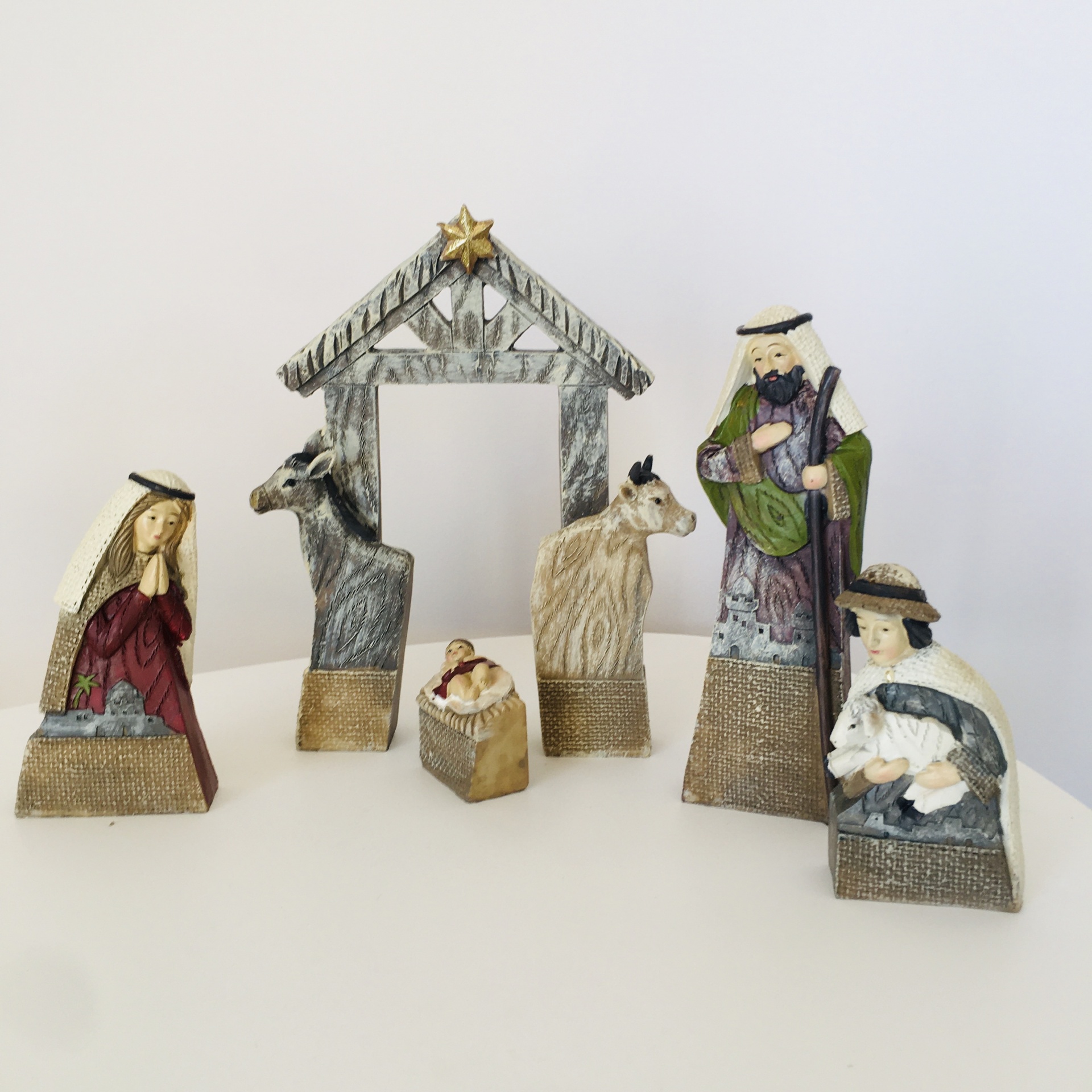 Conjunto de presépio com figuras de resina em cores e estrutura de celeiro com estrela