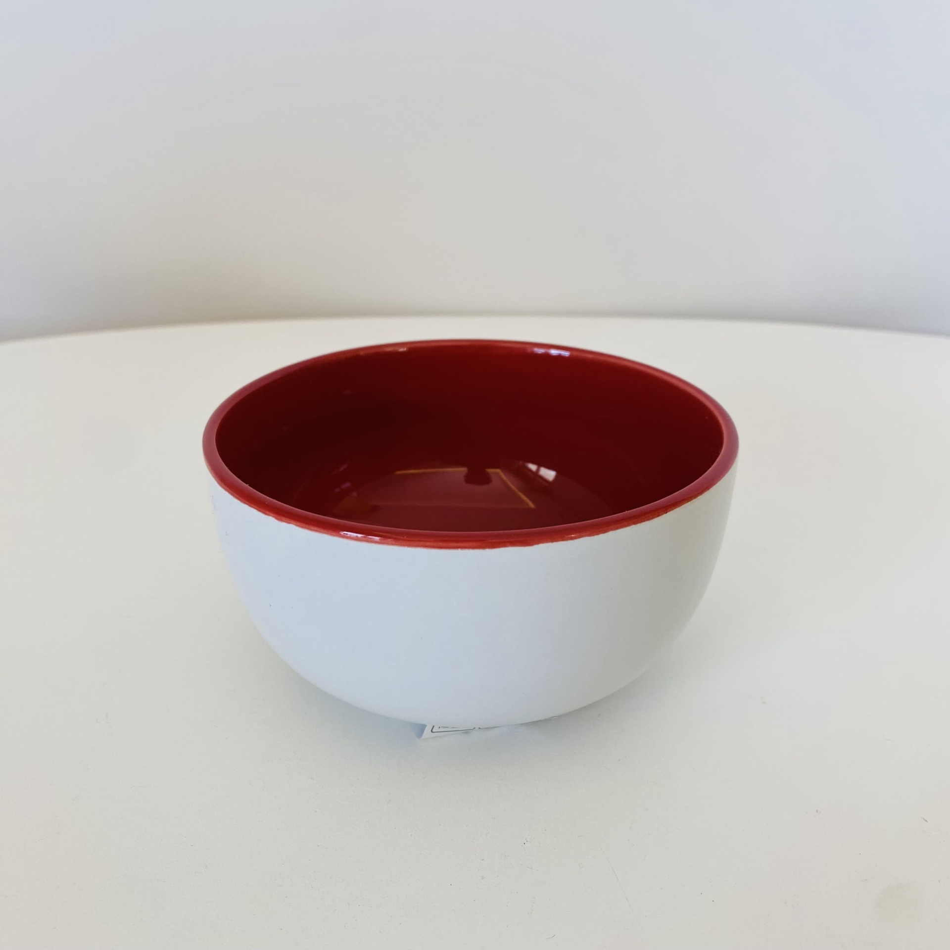 Tigela cerâmica branca e vermelha sobre superfície branca
