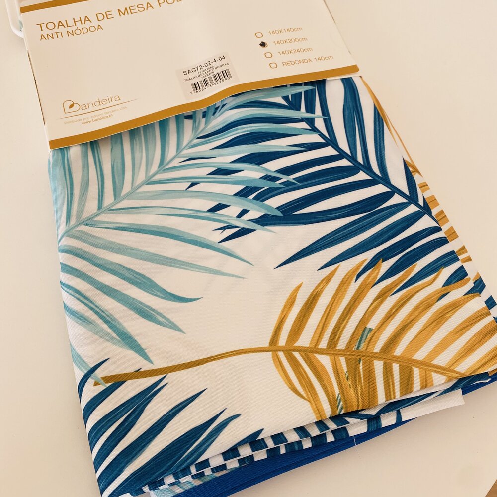 Toalha de mesa anti nódoa com padrão de folhas coloridas e embalagem com etiqueta