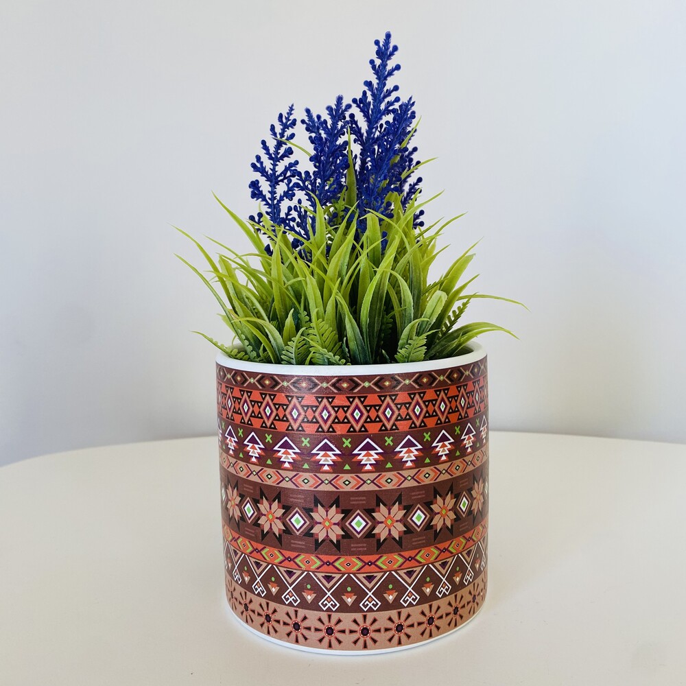 Vaso decorativo com plantas artificiais verdes e flores azuis em vaso com padrão geométrico marron