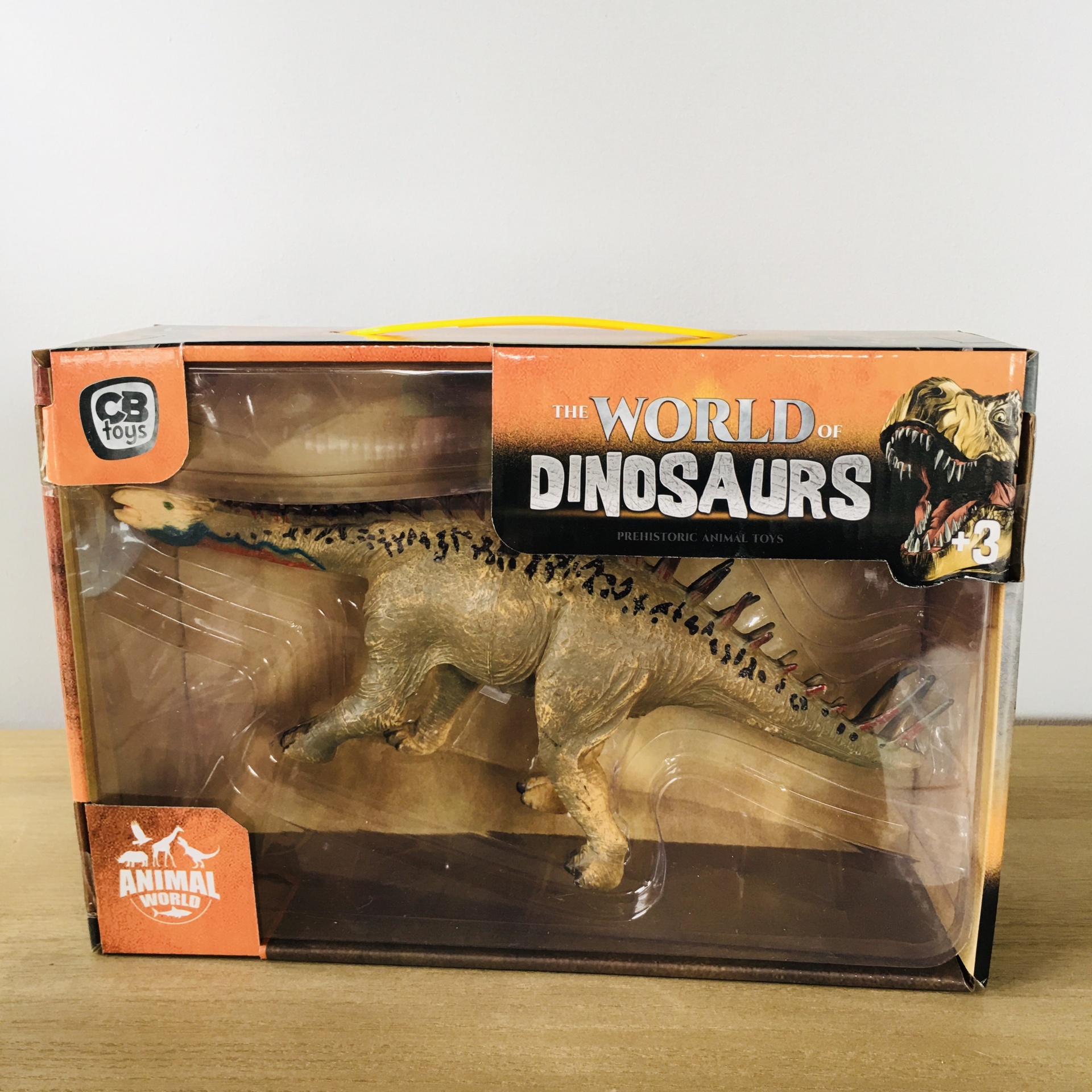 Figura de dinossauro amarelo e castanho na embalagem THE WORLD OF DINOSAURS