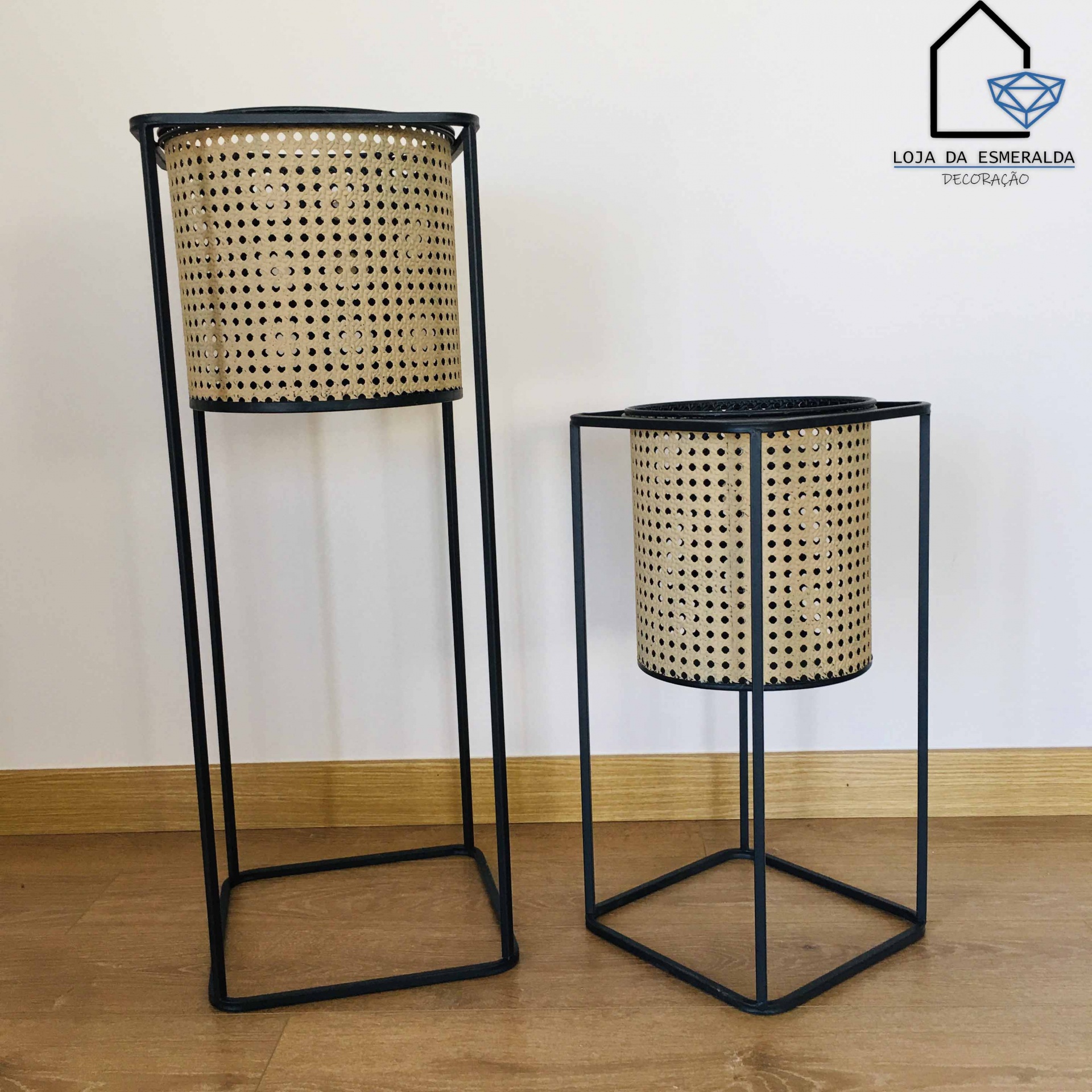 Dois cachepots decorativos com estrutura preta e cestos trançados naturais em fundo branco.