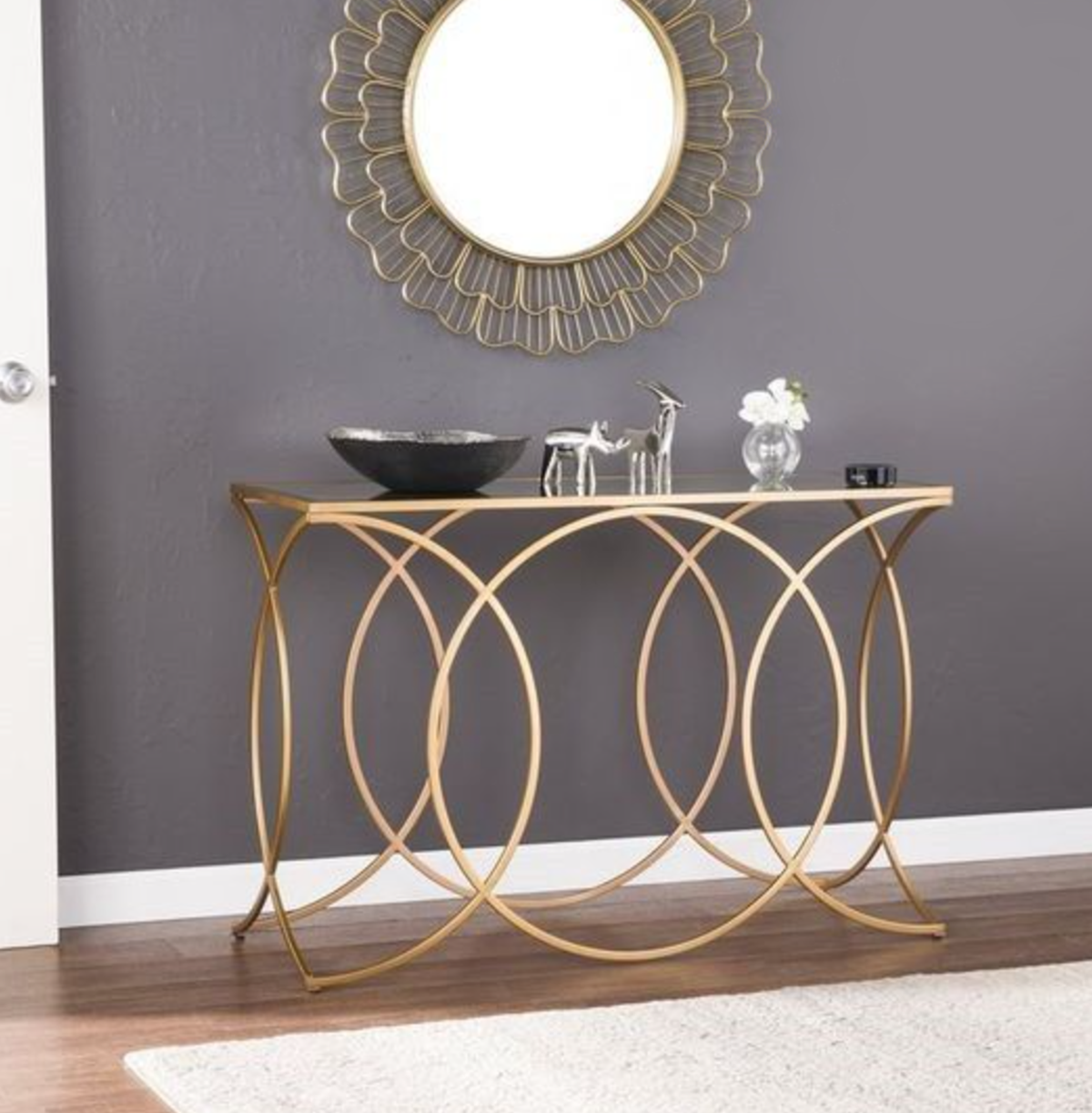 Consola metálica dourada com tampo vidro e espelho redondo dourado na parede