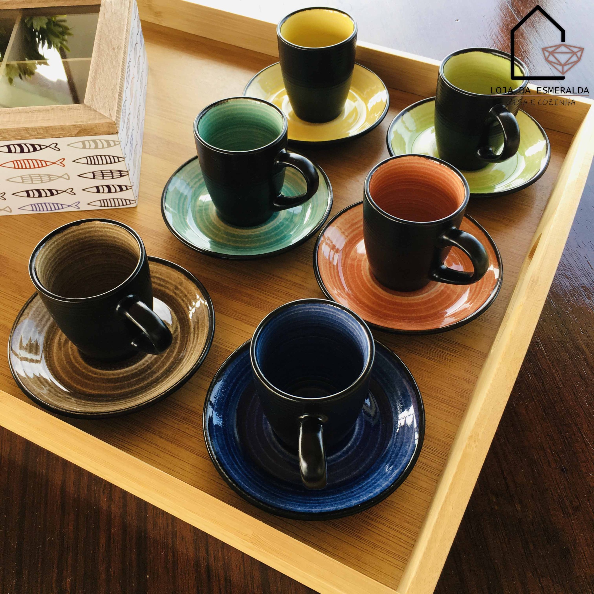 Chávenas de café coloridas com pires numa bandeja de madeira