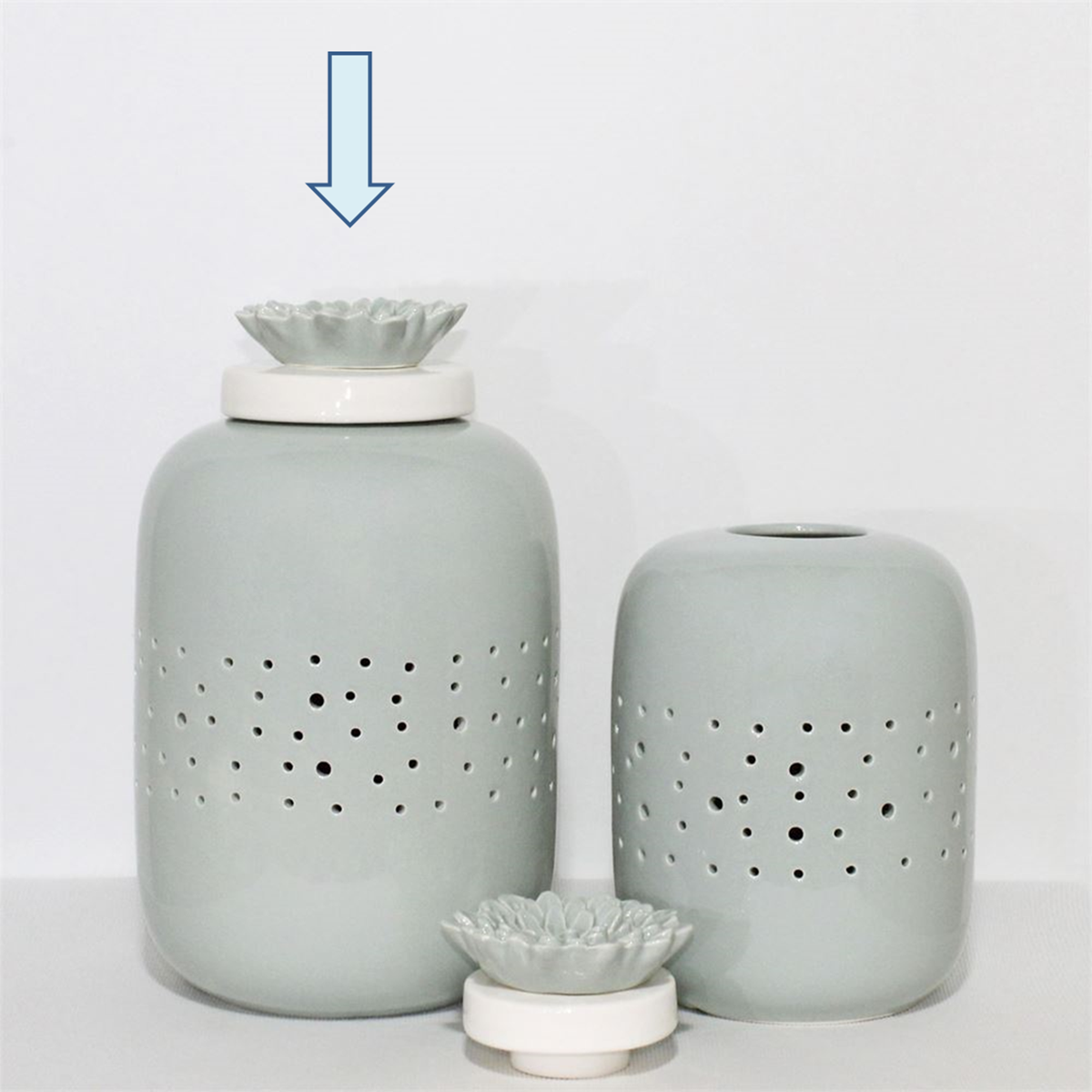Dois jarros de cerâmica cinza claro com tampas brancas e flores decorativas.