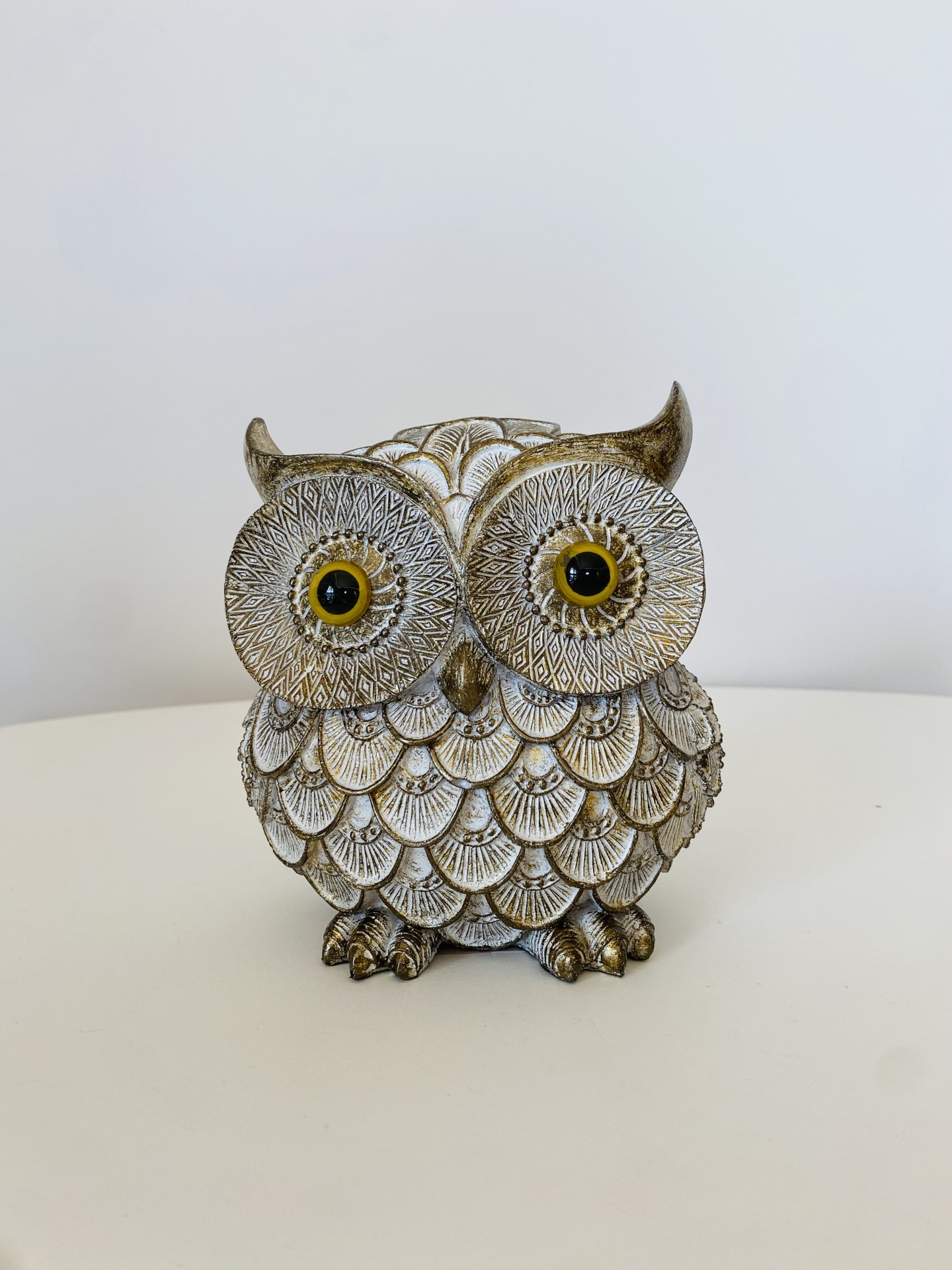 Estatueta de coruja decorativa branca e dourada com olhos amarelos