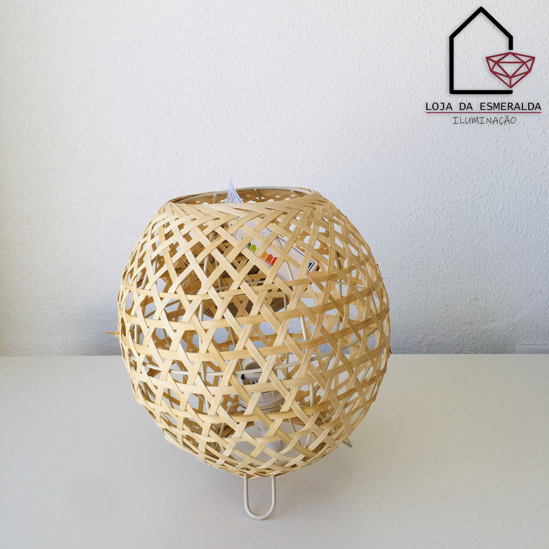 Candeeiro de mesa com cúpula em vime natural entrelaçado e base branca.