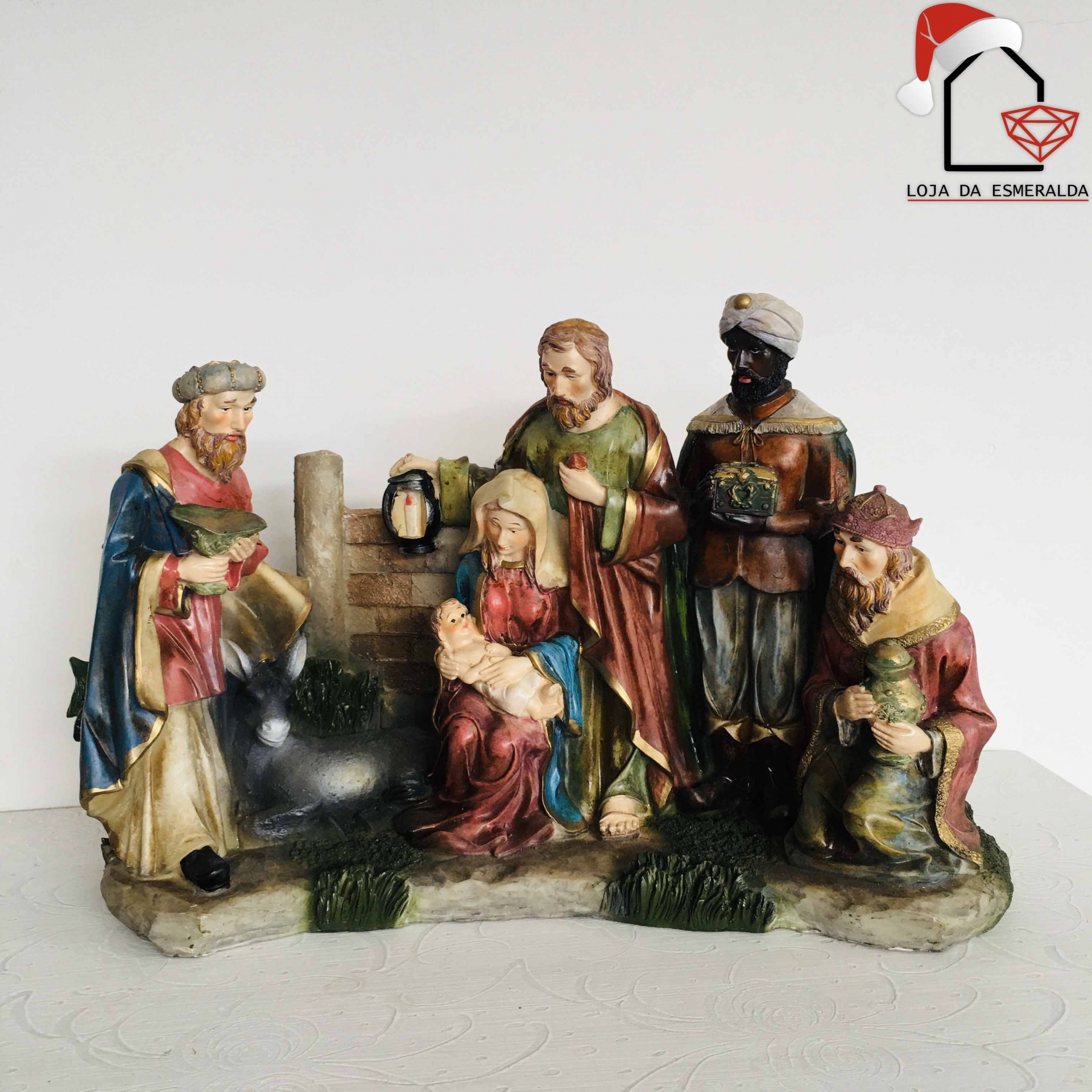 Estatueta de presépio com cinco figuras policromadas em resina sobre base simulando pedra e relva